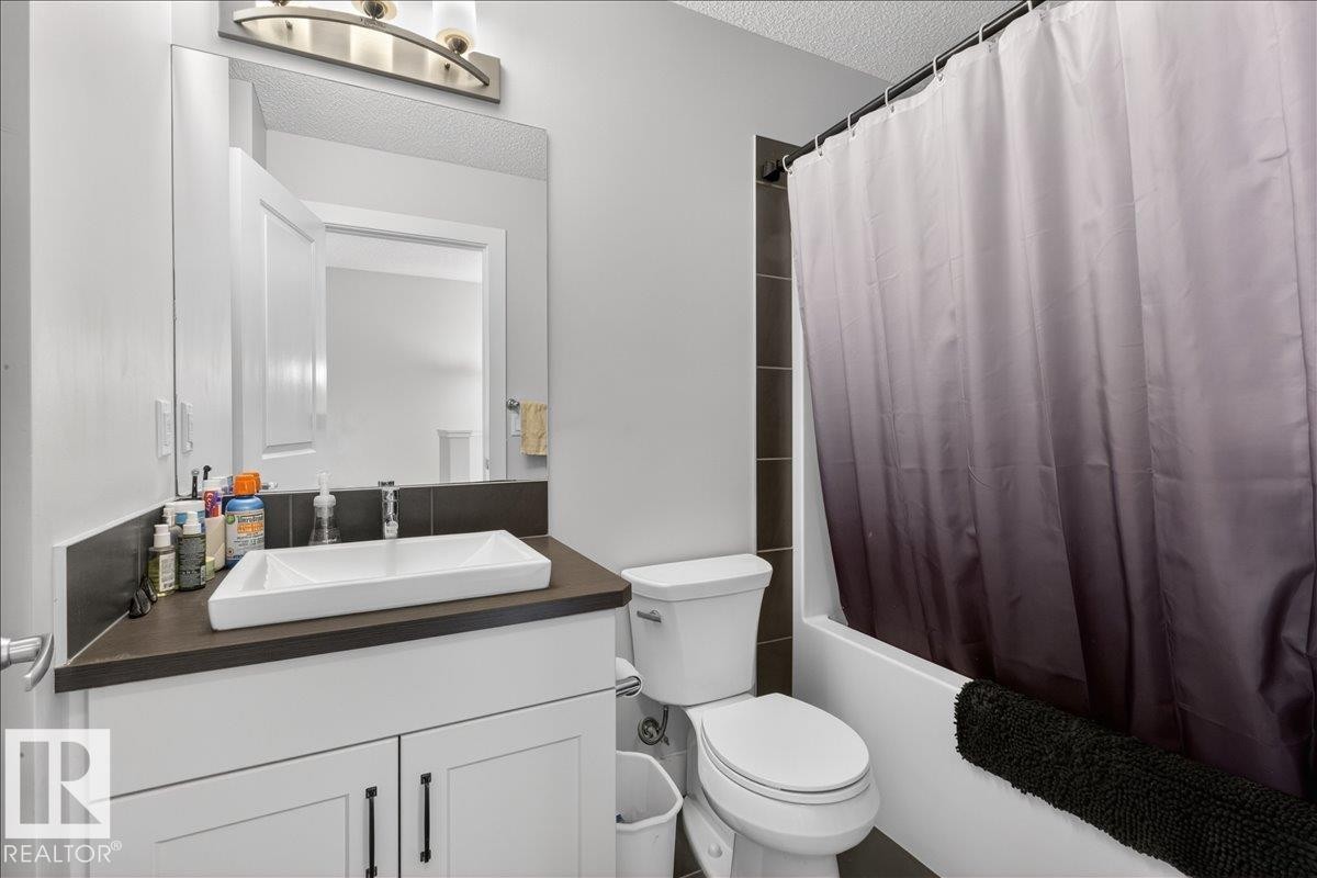 Bathroom featuring a vanity with a rectangular vessel sink, a toilet, and a shower with a dark-tiled surround - 9034 Rosenthal Link, Edmonton, AB - Indoor Photo Showing Bathroom