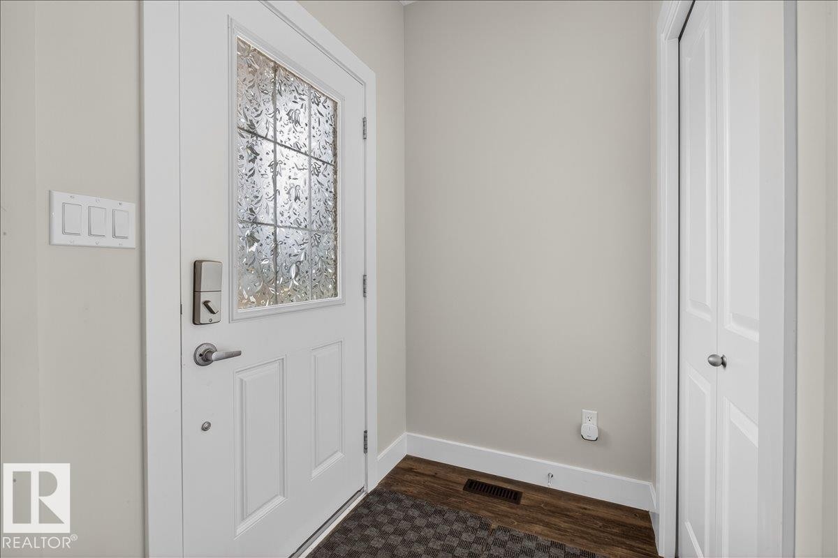 Entryway featuring a white door with decorative glass, a modern smart lock, and hardwood flooring - 9034 Rosenthal Link, Edmonton, AB - Indoor Photo Showing Other Room