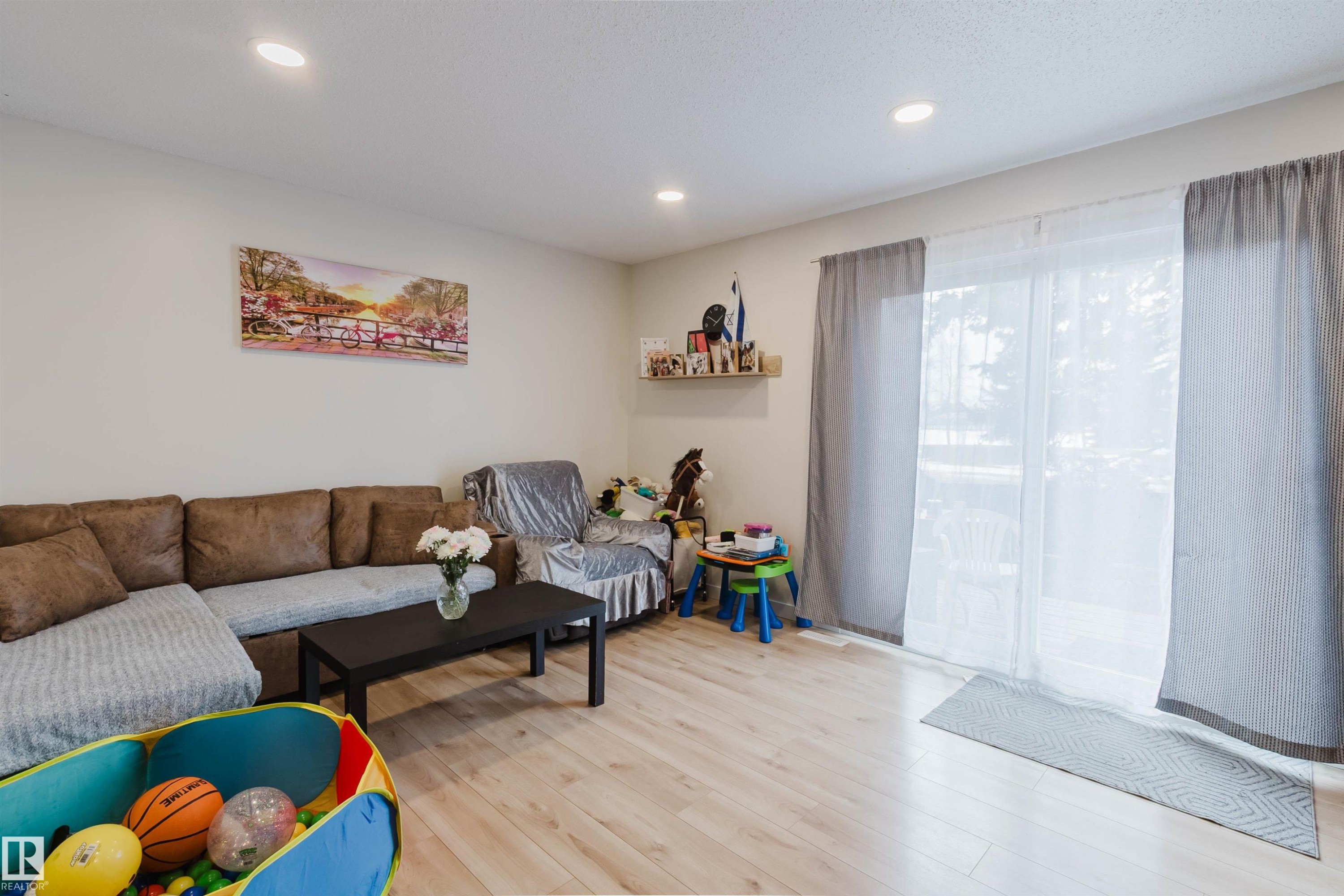 Living area featuring light-toned flooring, recessed lighting, and sliding glass doors - 18088 93 Avenue Nw, Edmonton, AB - Indoor Photo Showing Living Room