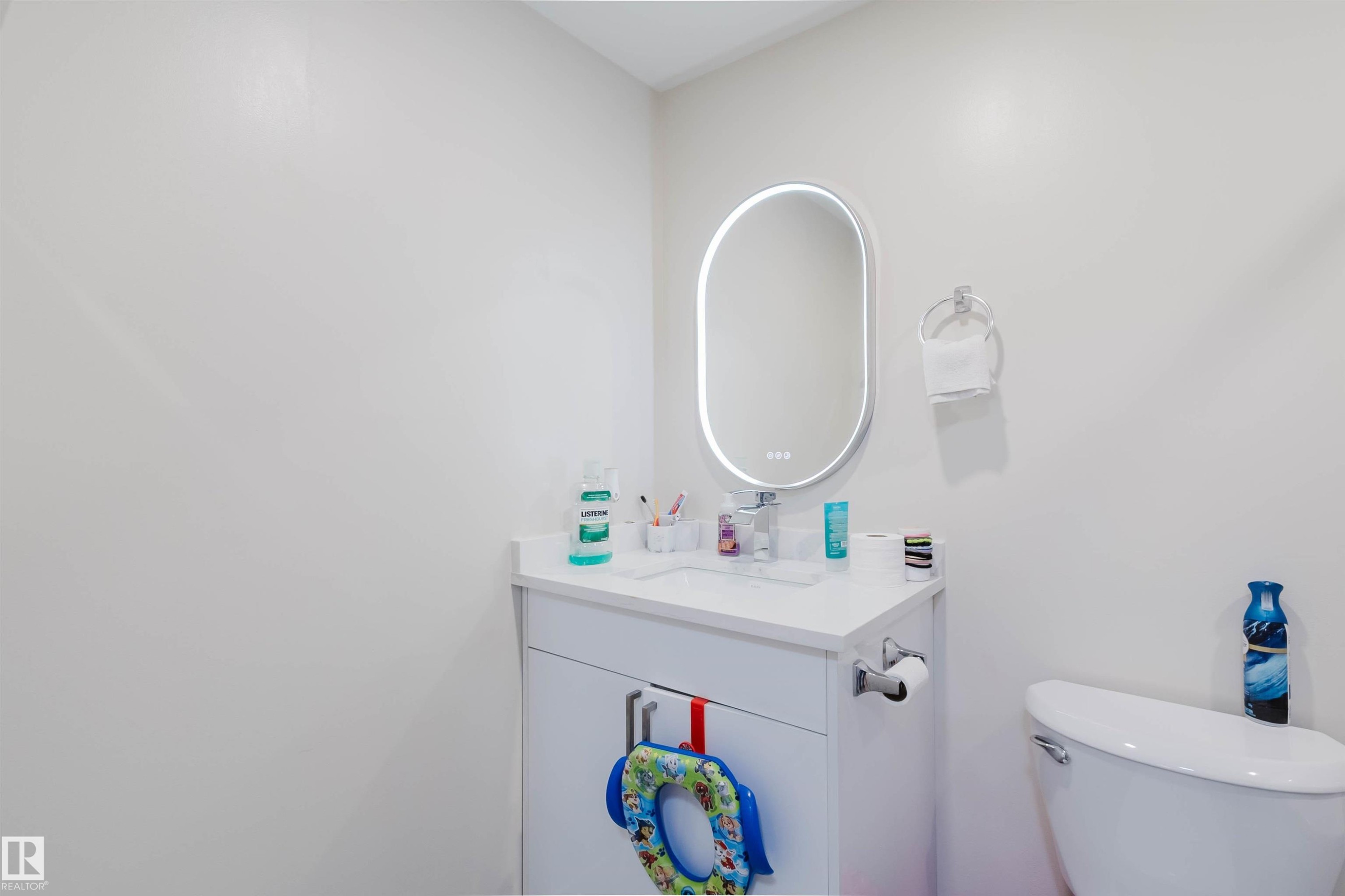 Bathroom featuring a white vanity with a white countertop, a white sink, and an illuminated oval mirror - 18088 93 Avenue Nw, Edmonton, AB - Indoor Photo Showing Bathroom