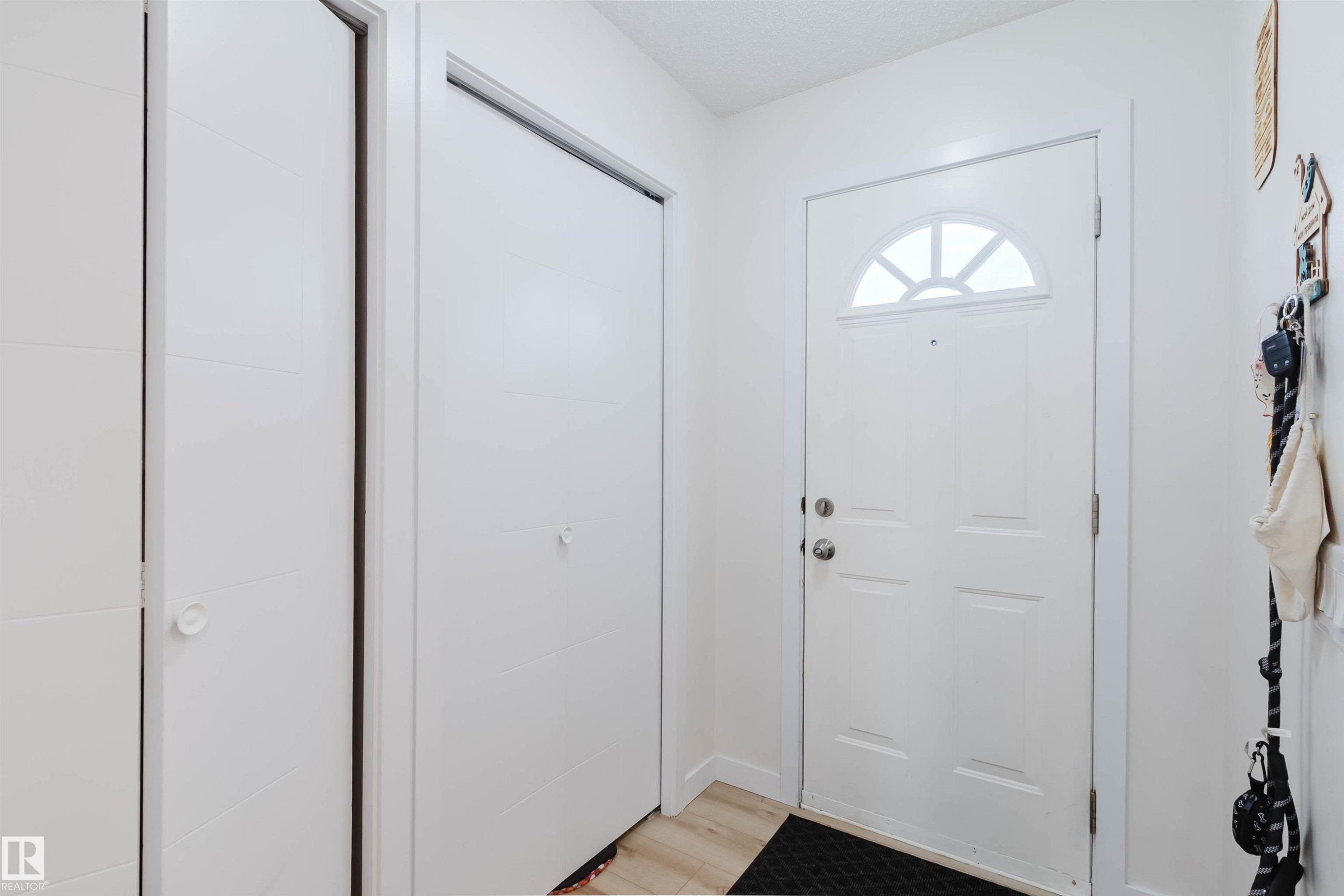 Entryway with a white front door featuring an arched window, a bi-fold closet, and light-colored flooring - 18088 93 Avenue Nw, Edmonton, AB - Indoor Photo Showing Other Room