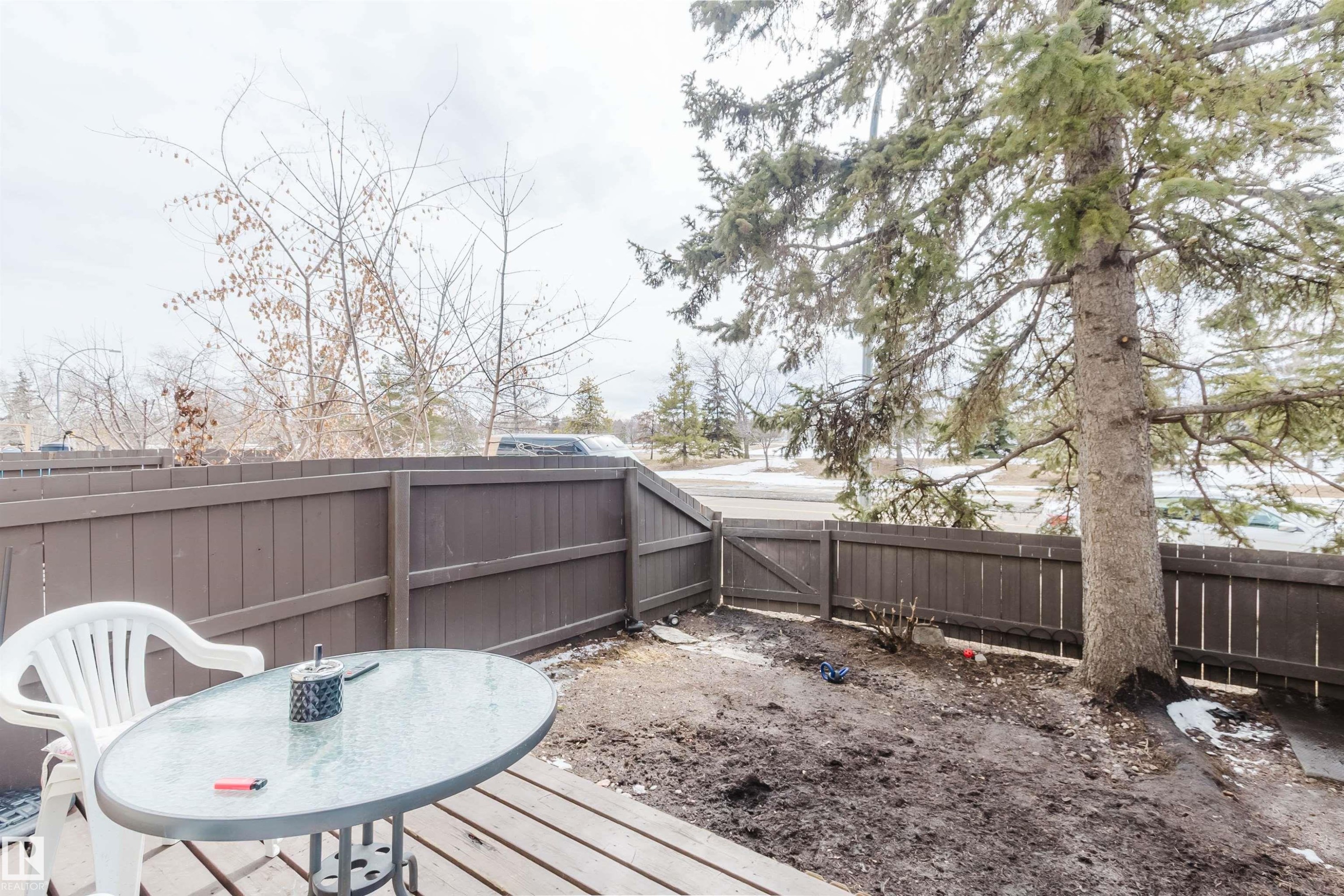 The property features a fenced yard with a large evergreen tree and a small wooden gate - 18088 93 Avenue Nw, Edmonton, AB - Outdoor With Deck Patio Veranda