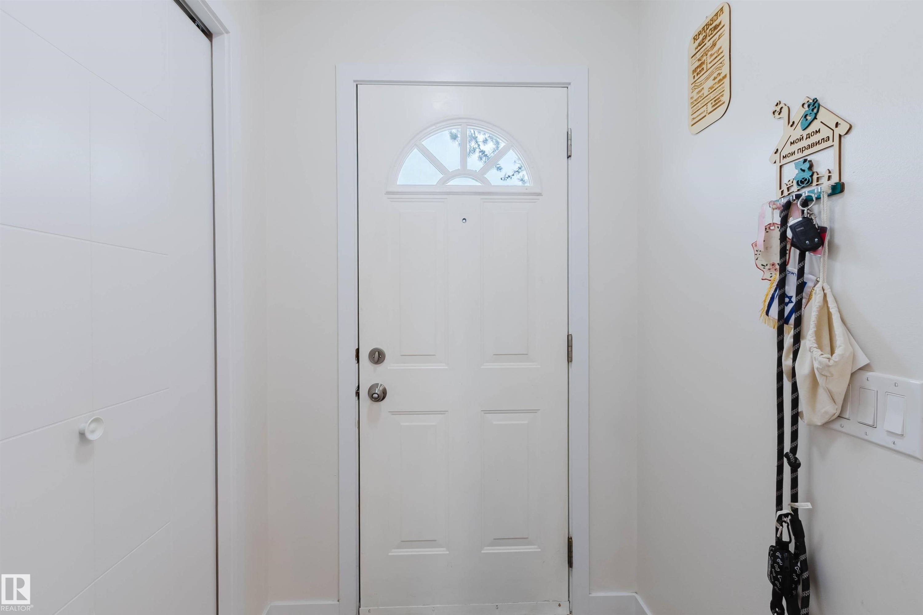 The property features a white paneled door with an arched window, complemented by a white closet door with horizontal detailing - 18088 93 Avenue Nw, Edmonton, AB - Indoor Photo Showing Other Room