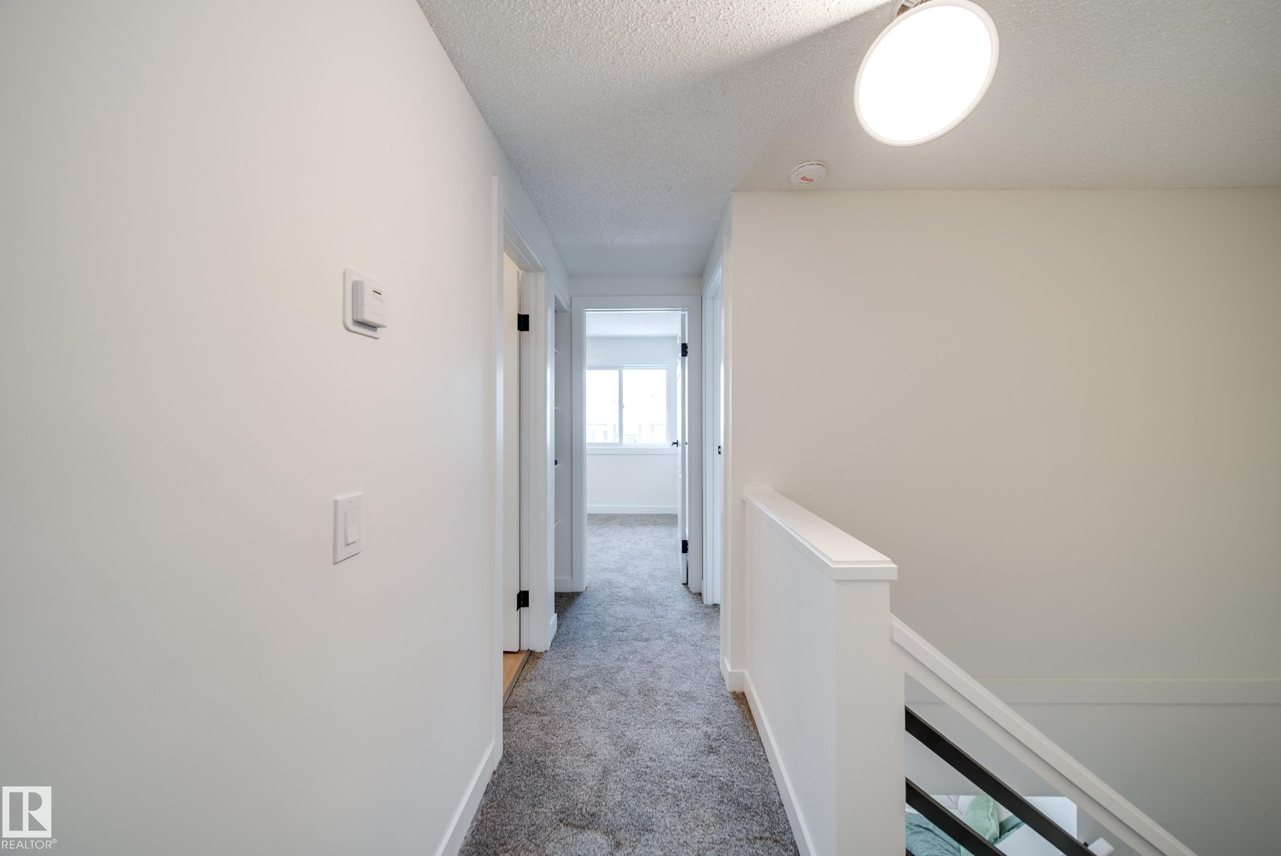 The property features a hallway with light gray carpeting, white walls, and a ceiling light fixture - 125 Woodborough Way, Edmonton, AB - Indoor Photo Showing Other Room