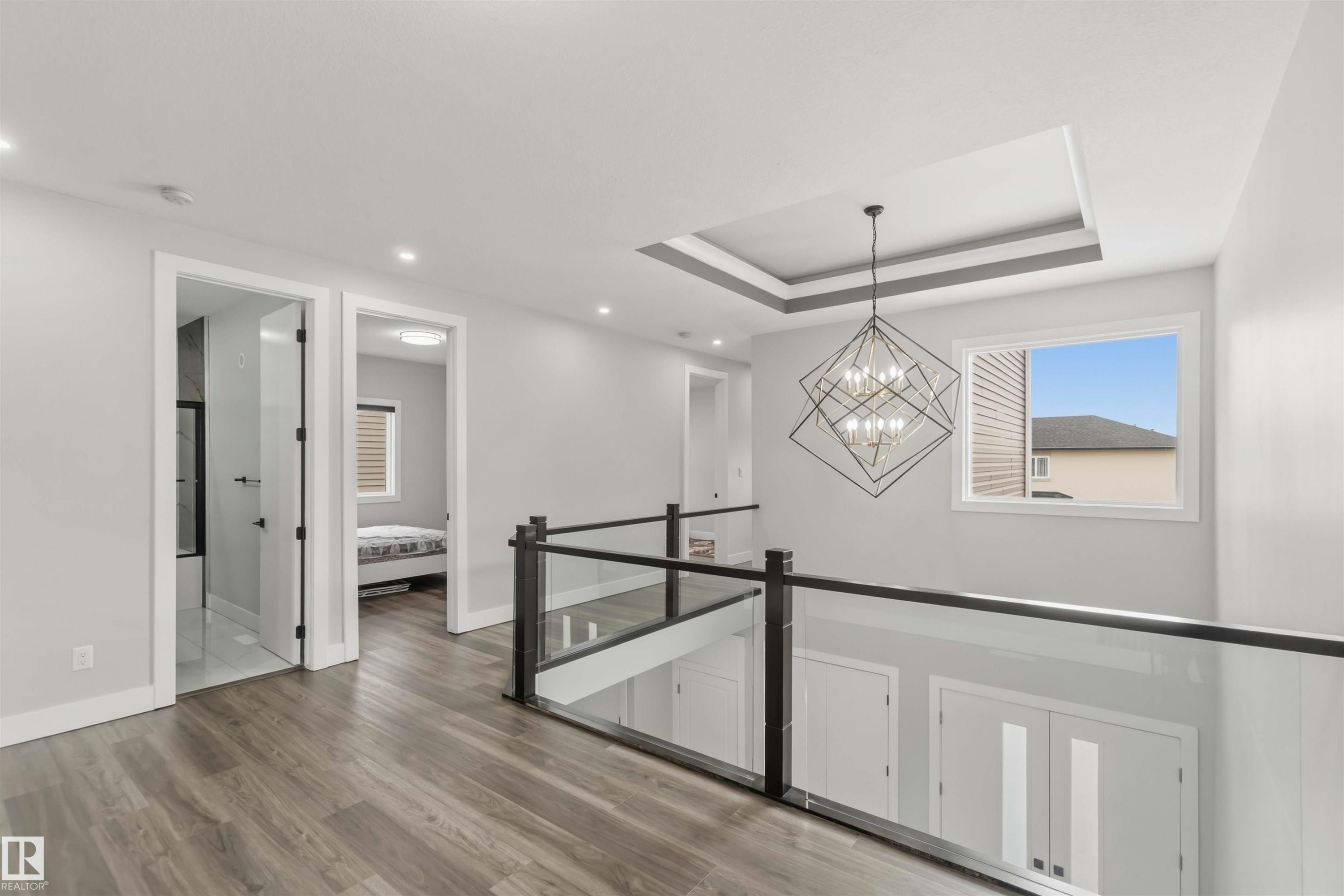 The property features a hallway with hardwood flooring, recessed lighting, and a modern chandelier - 1520 151 Avenue, Edmonton, AB - Indoor Photo Showing Other Room