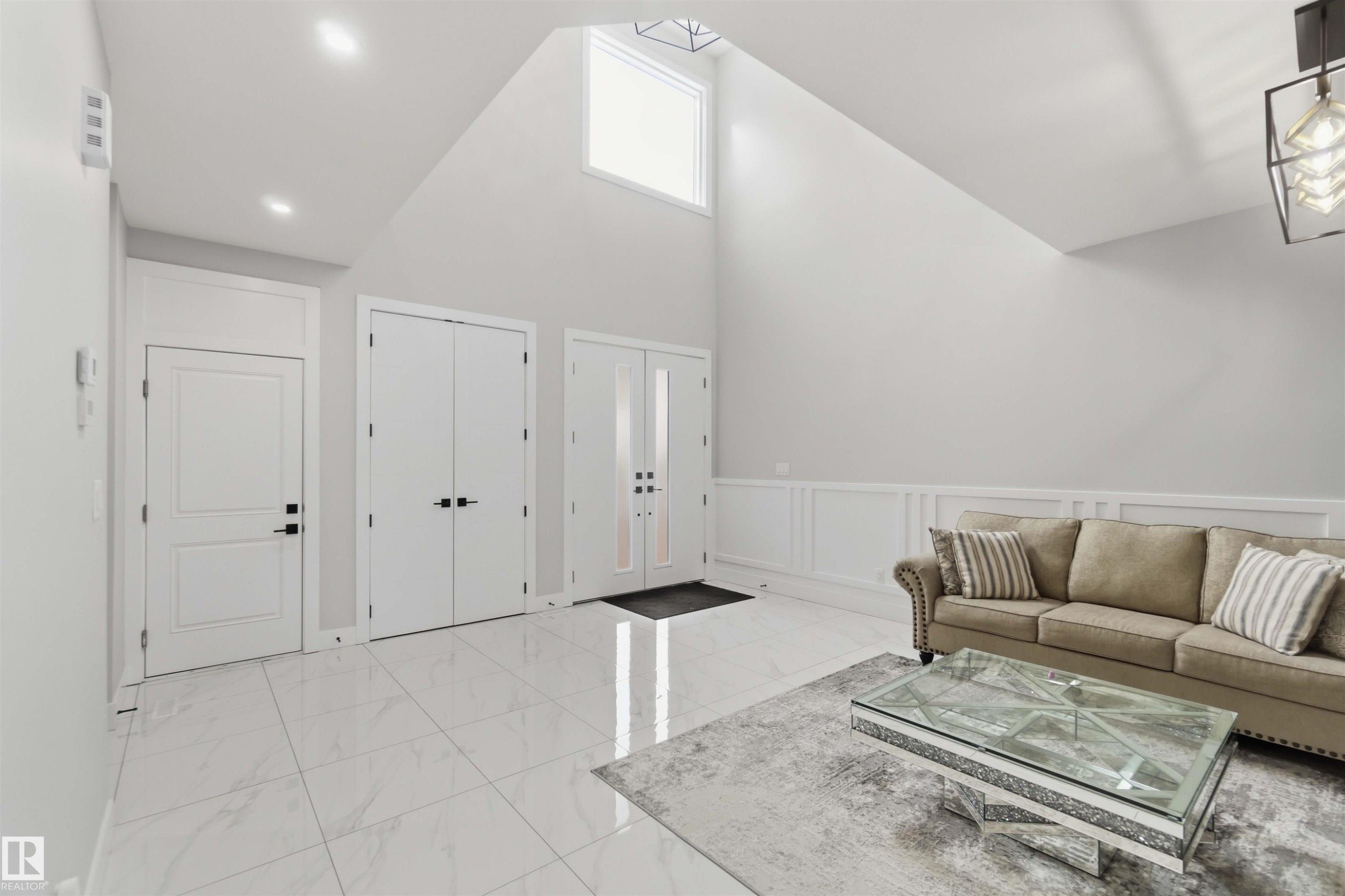 The property features high vaulted ceilings with a transom window providing natural light, recessed lighting, and white tile flooring - 1520 151 Avenue, Edmonton, AB - Indoor