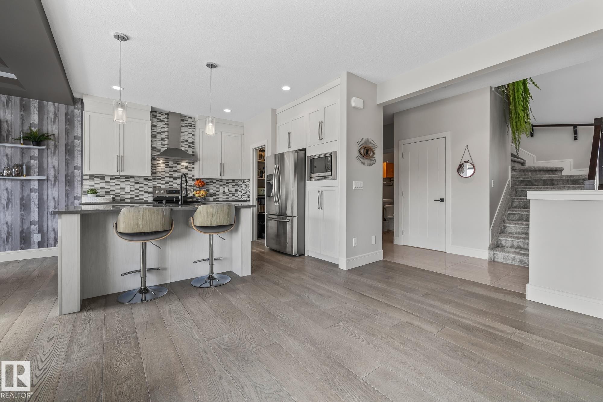 Open concept kitchen featuring an island with seating, stainless steel appliances, and light-toned flooring - 3864 Robins Crescent, Edmonton, AB - Indoor Photo Showing Kitchen With Upgraded Kitchen