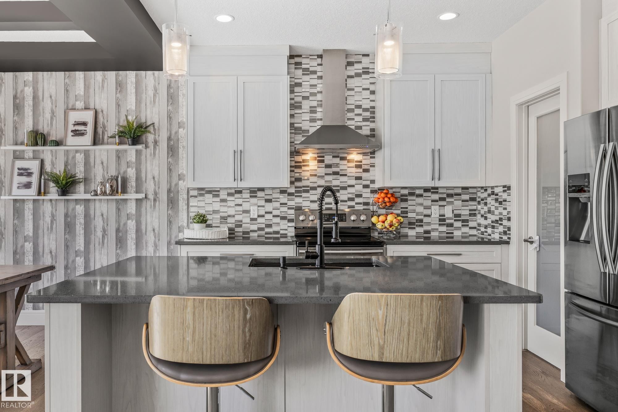 Modern kitchen featuring white cabinetry, a stylish mosaic tile backsplash, stainless steel appliances, and a central island with a dark countertop - 3864 Robins Crescent, Edmonton, AB - Indoor Photo Showing Kitchen With Upgraded Kitchen