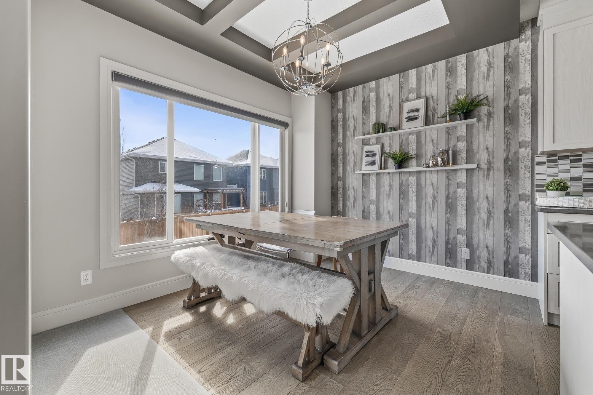 The dining area features engineered hardwood flooring, a coffered ceiling, and a prominent feature wall with a wood plank pattern - 3864 Robins Crescent, Edmonton, AB - Indoor Photo Showing Dining Room
