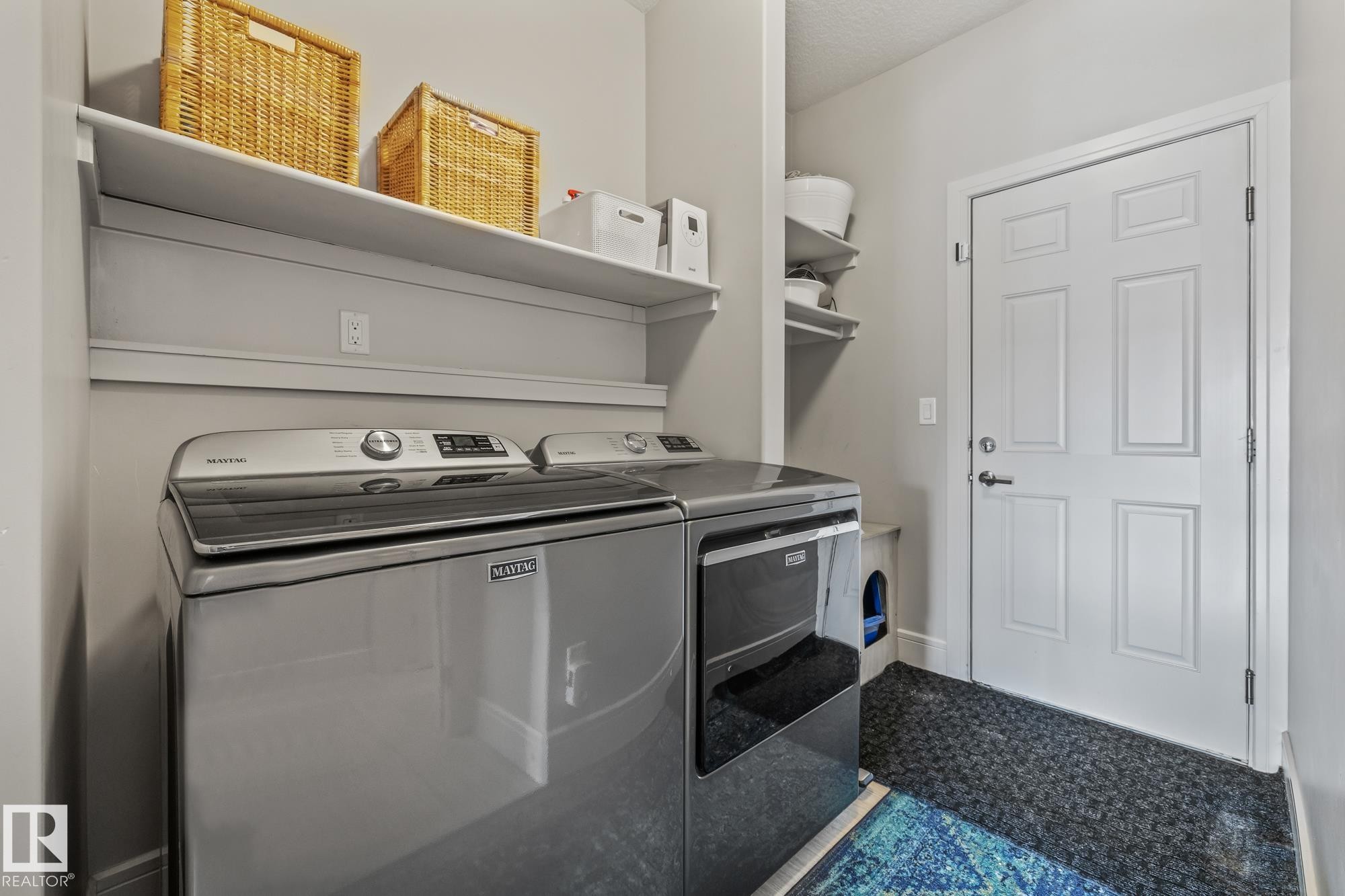 The laundry area features a washer and dryer, an overhead shelf, and additional wall-mounted shelving - 3864 Robins Crescent, Edmonton, AB - Indoor Photo Showing Laundry Room