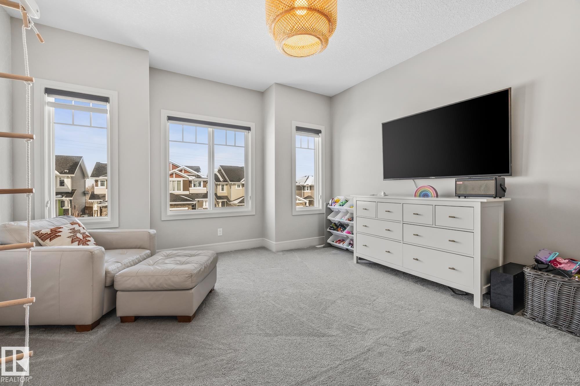 This spacious room features light grey carpeting, several large windows providing natural light, and a stylish woven light fixture - 3864 Robins Crescent, Edmonton, AB - Indoor Photo Showing Living Room