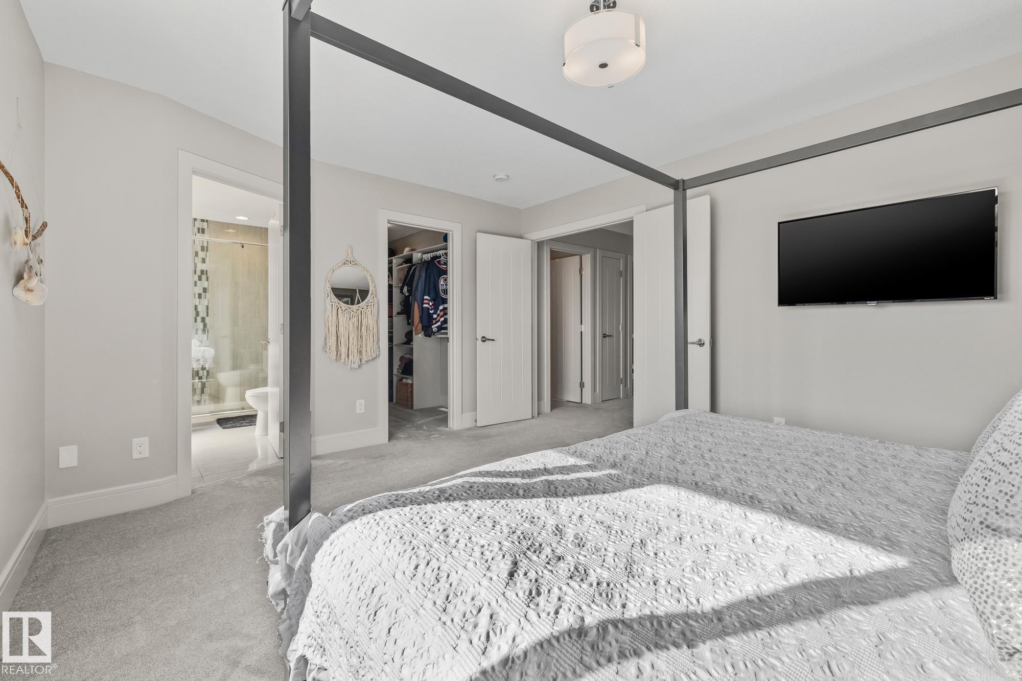 This room features soft gray carpeting, a ceiling-mounted light fixture, and an open doorway leading to a bathroom with a shower - 3864 Robins Crescent, Edmonton, AB - Indoor Photo Showing Bedroom
