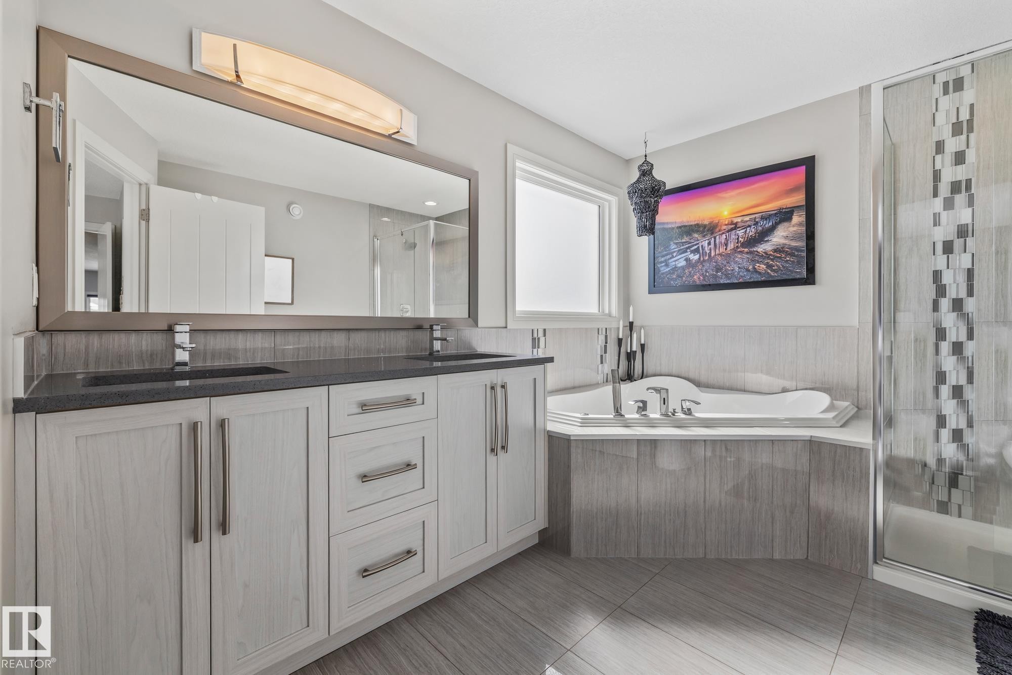 This bathroom features a double vanity with two sinks and a large mirror, a corner soaking tub, and a separate shower with a glass enclosure - 3864 Robins Crescent, Edmonton, AB - Indoor Photo Showing Bathroom