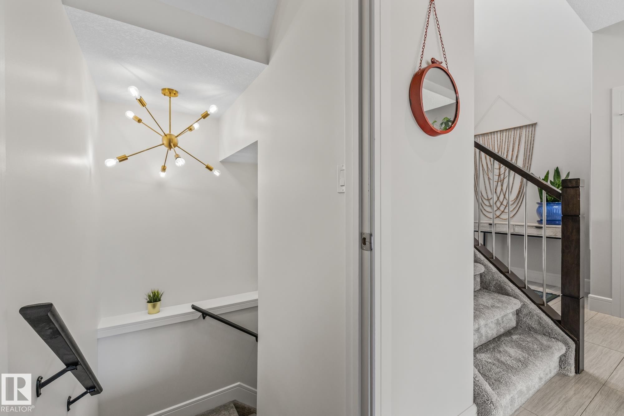 Entryway featuring a modern sputnik chandelier and a carpeted staircase with dark wood newel posts and handrails - 3864 Robins Crescent, Edmonton, AB - Indoor