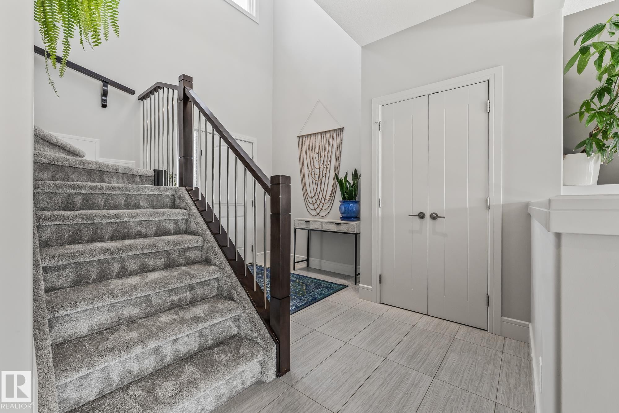 The property features a staircase with carpeted treads and a dark wood and metal railing - 3864 Robins Crescent, Edmonton, AB - Indoor Photo Showing Other Room
