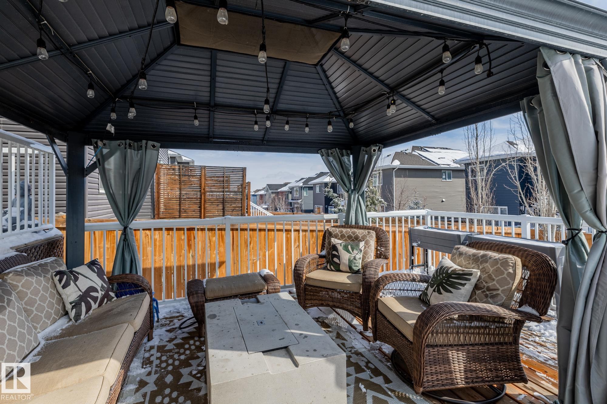The property features a covered outdoor deck area with a metal gazebo structure, string lights, and privacy curtains - 3864 Robins Crescent, Edmonton, AB - Outdoor With Deck Patio Veranda With Exterior