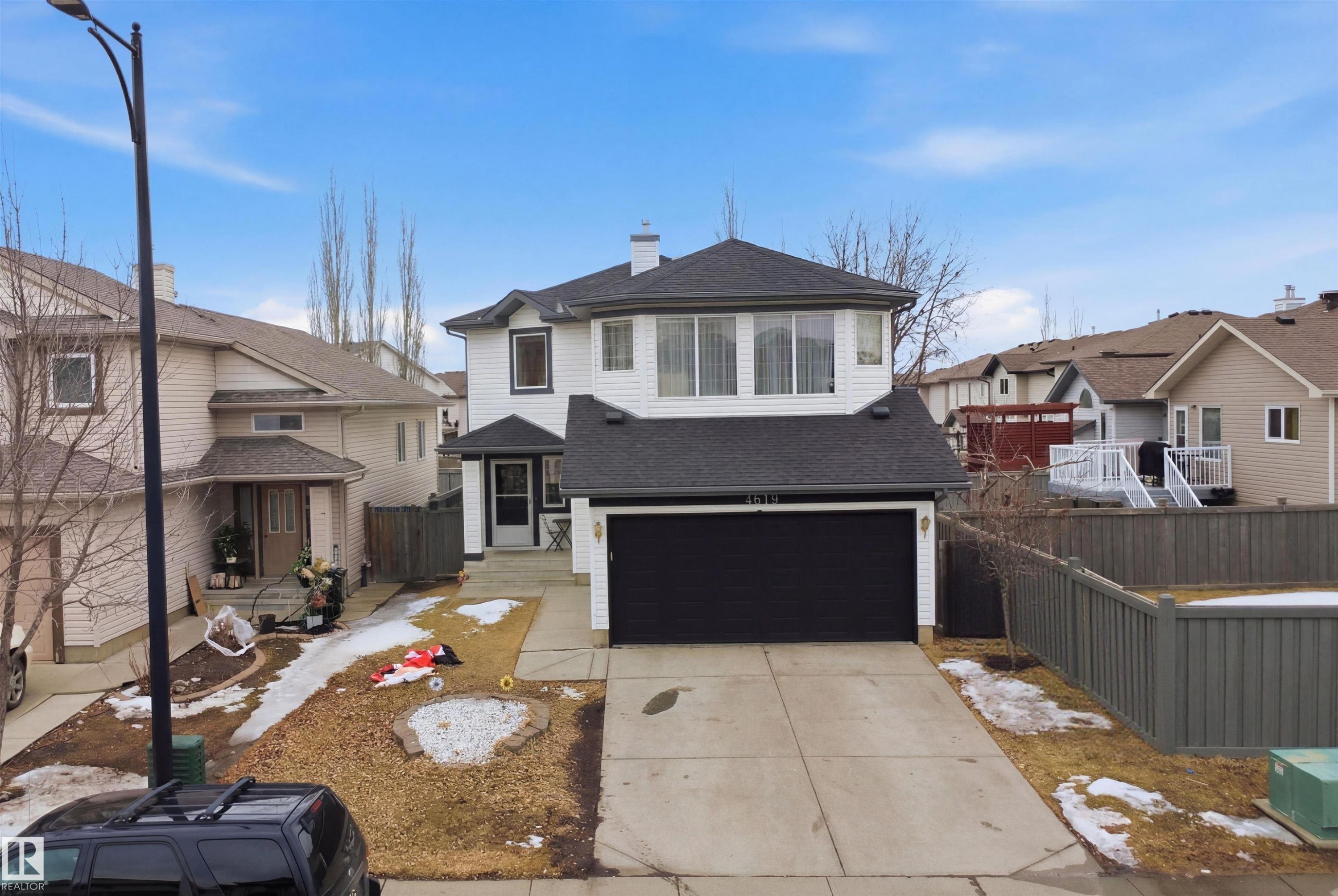 The property features a white exterior with a dark roof and a two-car garage - 4619 202 Street, Edmonton, AB - Outdoor