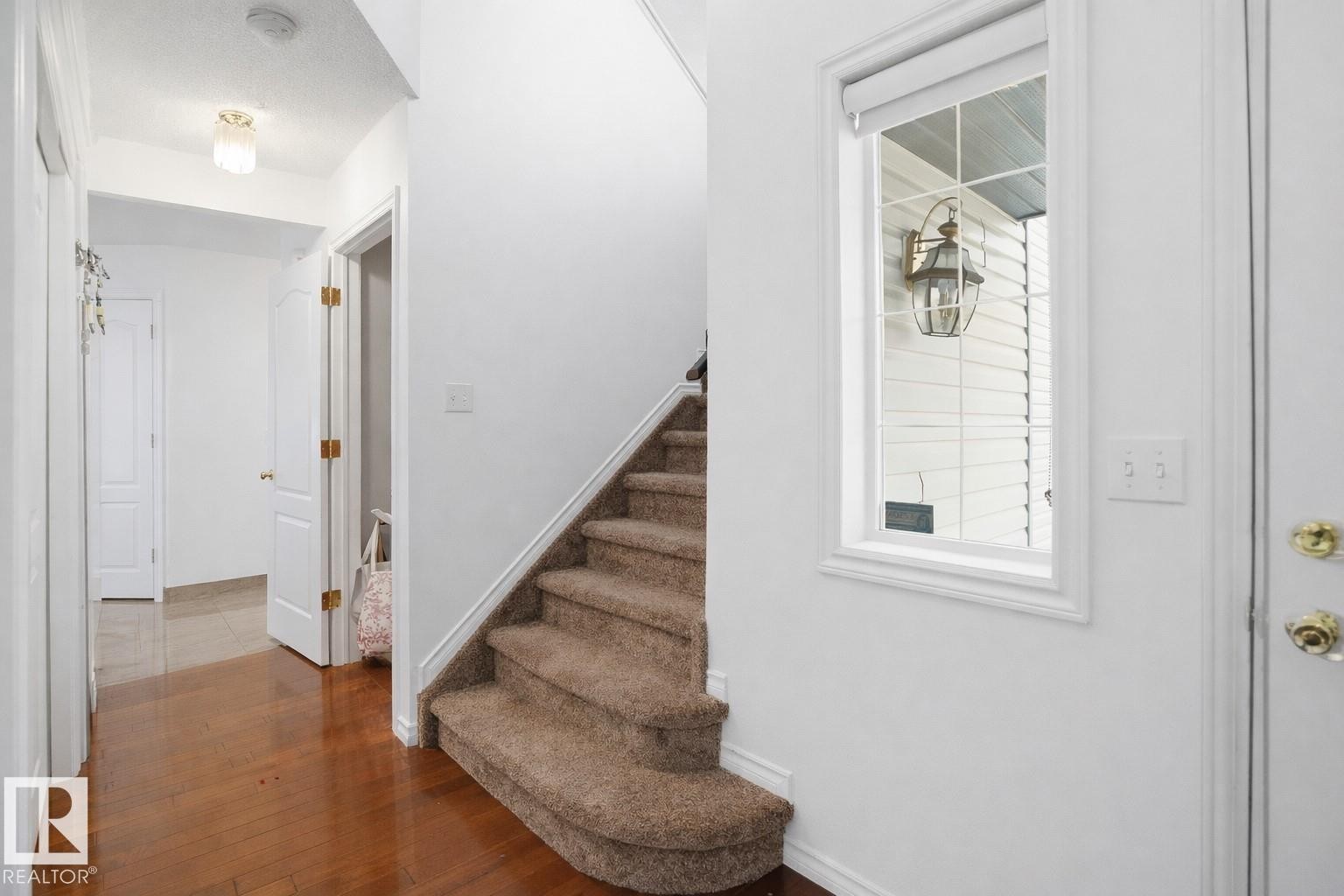 Entryway featuring hardwood floors, a carpeted staircase, and a window providing natural light - 4619 202 Street, Edmonton, AB - Indoor Photo Showing Other Room