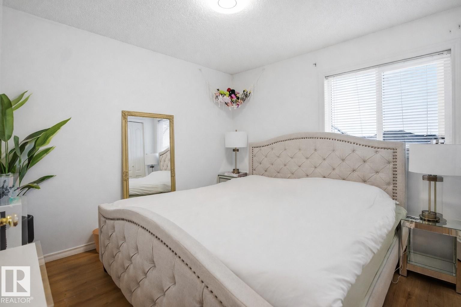 The bedroom features hardwood floors, white walls, and a window with blinds - 4619 202 Street, Edmonton, AB - Indoor Photo Showing Bedroom
