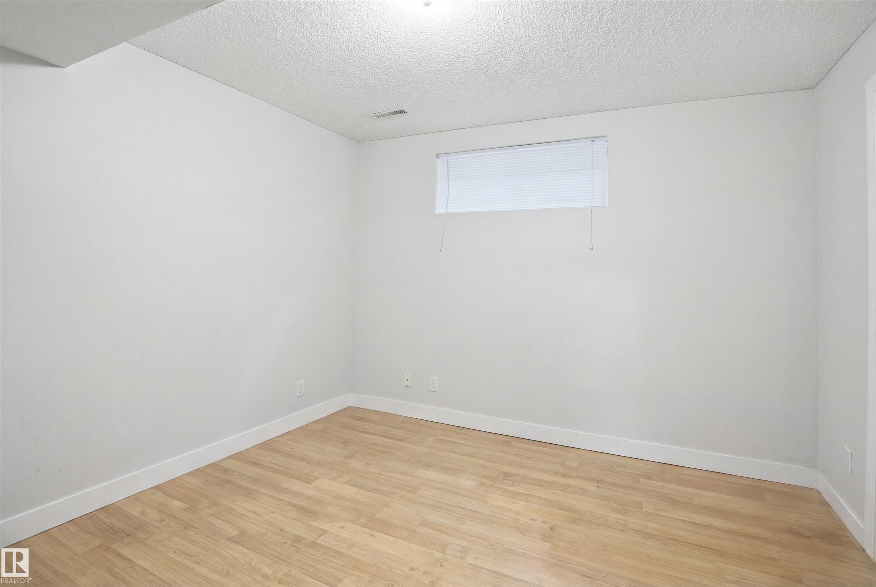 This bright room features light-toned flooring, white walls, and a window with blinds - 4619 202 Street, Edmonton, AB - Indoor Photo Showing Other Room