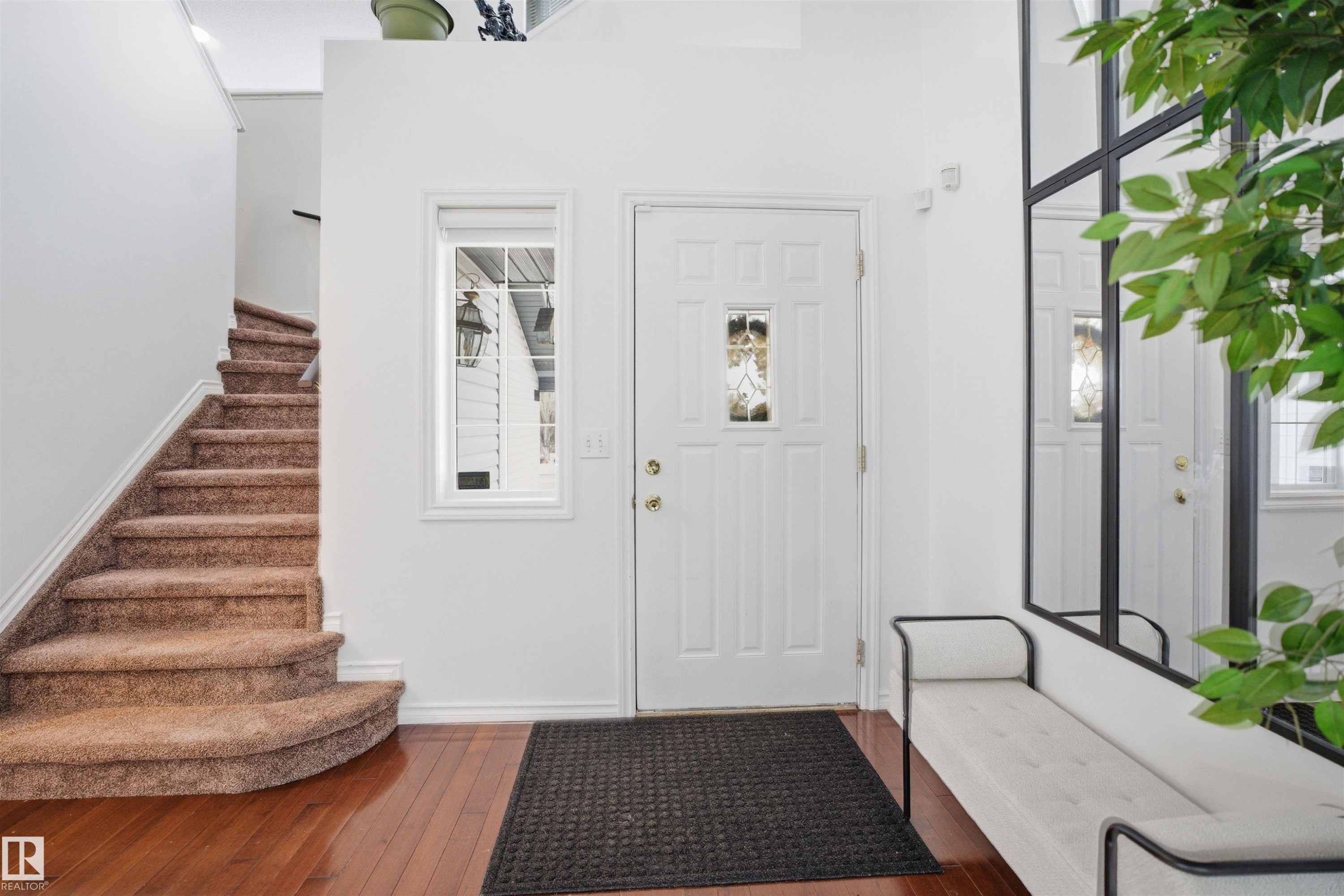 Welcoming entryway featuring hardwood flooring, a white front door with decorative glass, and a carpeted staircase - 4619 202 Street, Edmonton, AB - Indoor Photo Showing Other Room