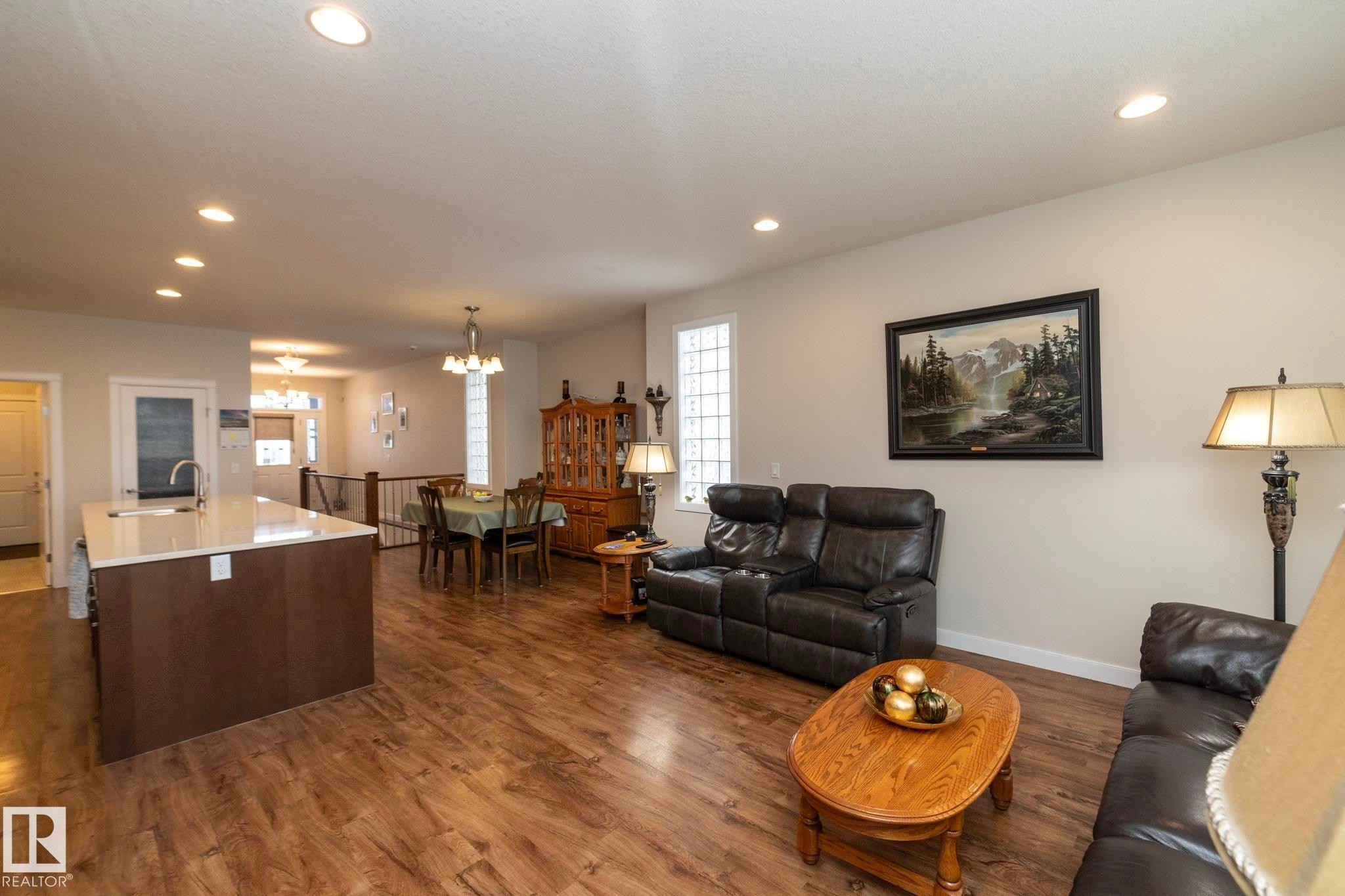 The property features a spacious open-concept living area with wood-look flooring and recessed lighting - 307 Ravine Close, Devon, AB - Indoor Photo Showing Living Room