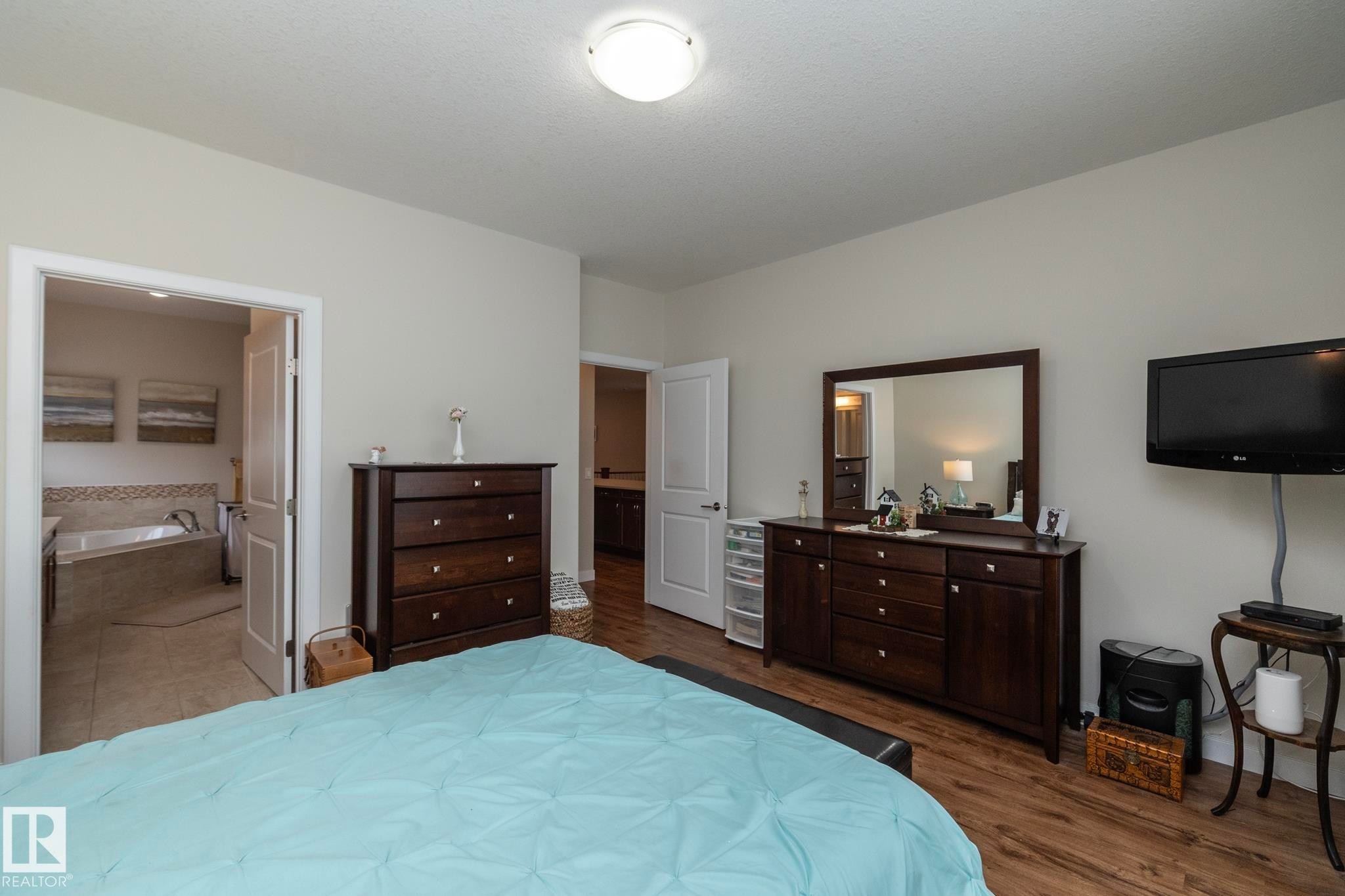 Spacious room featuring light-colored walls, wood-look flooring, and a ceiling light fixture - 307 Ravine Close, Devon, AB - Indoor Photo Showing Bedroom