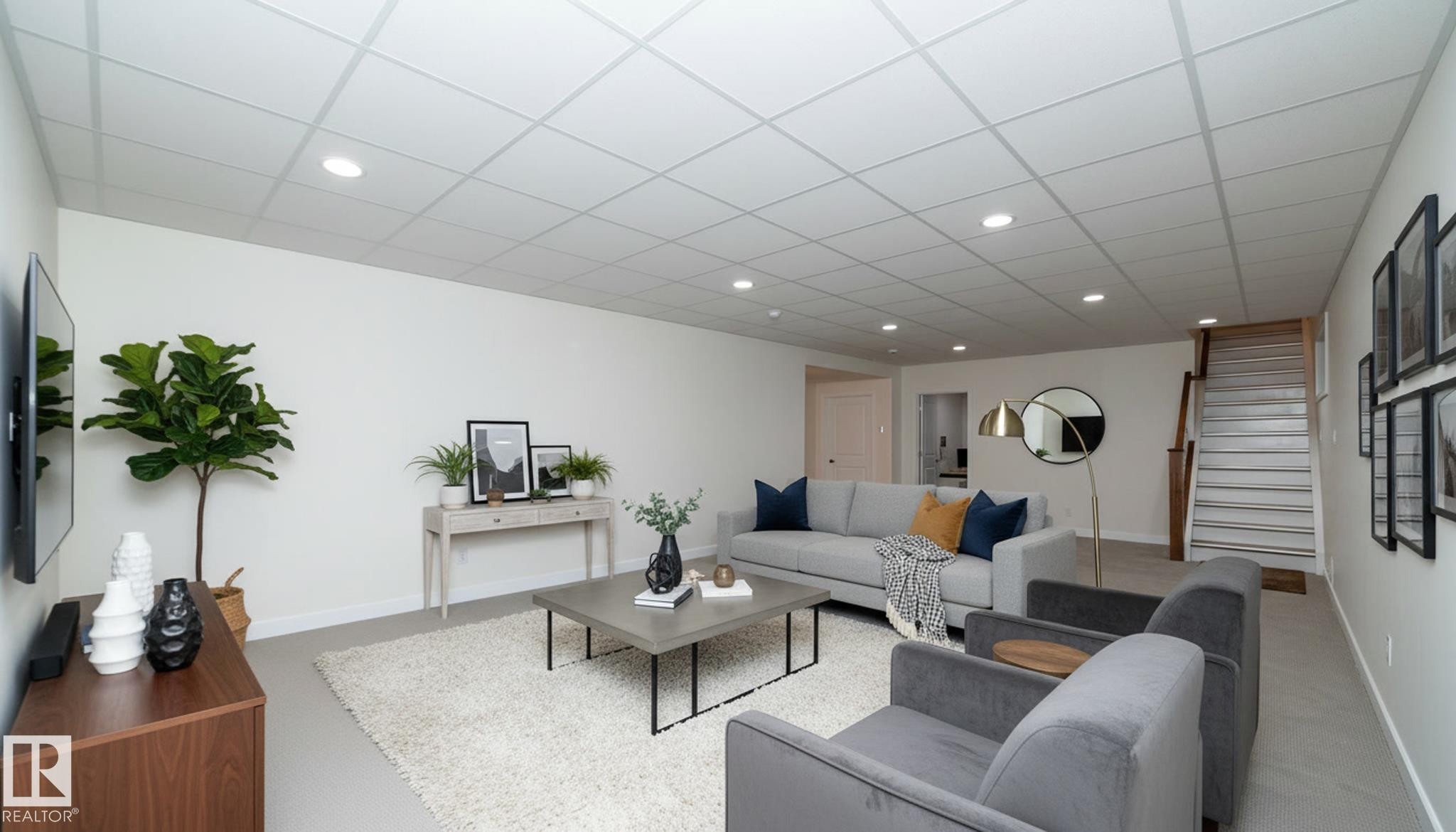 Spacious open concept living area featuring a drop ceiling with recessed lighting, light-colored walls, and a staircase with wooden handrails - 307 Ravine Close, Devon, AB - Indoor Photo Showing Other Room