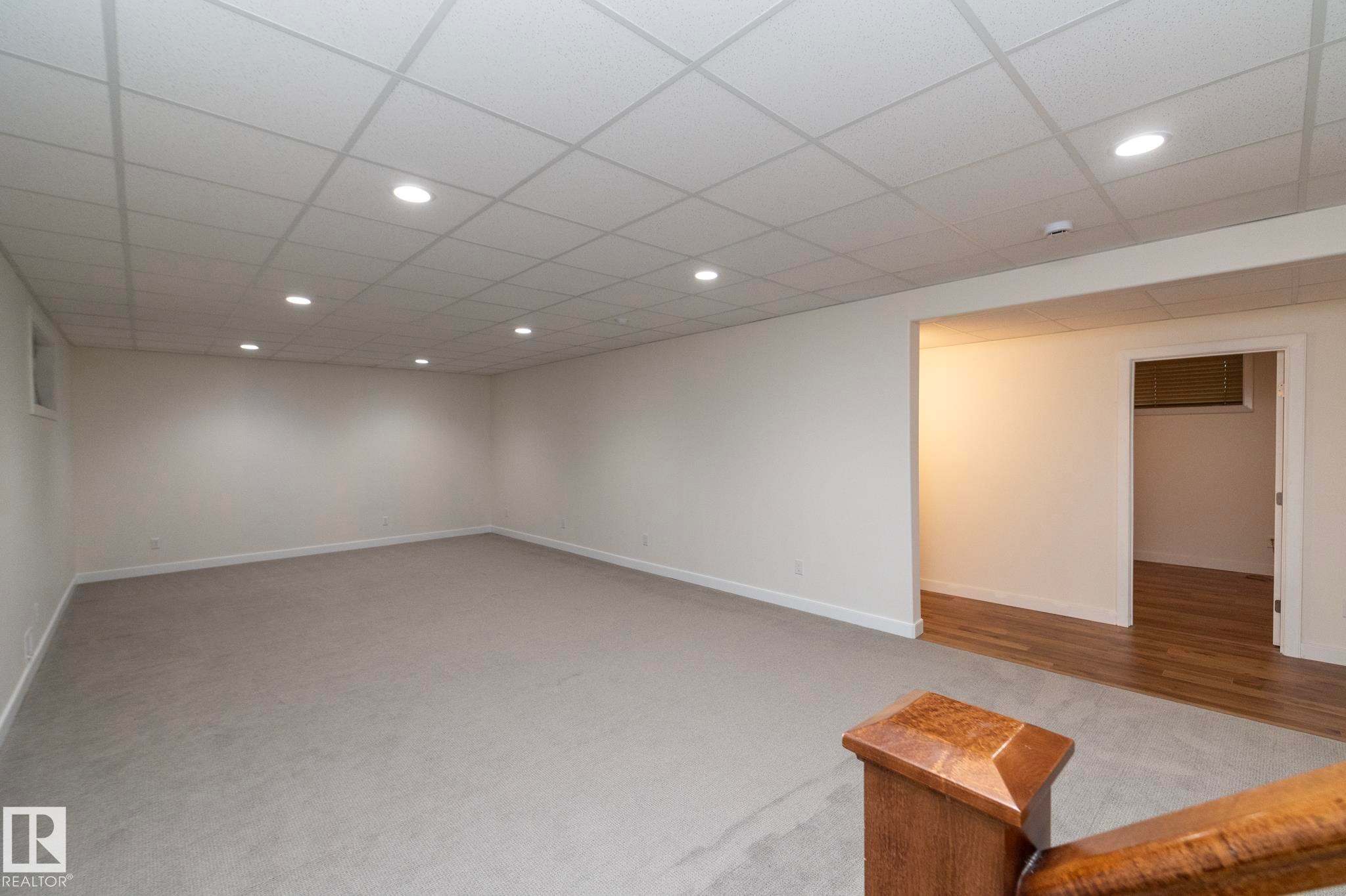 Spacious area featuring light grey carpeting, recessed lighting, and a white drop ceiling - 307 Ravine Close, Devon, AB - Indoor Photo Showing Other Room