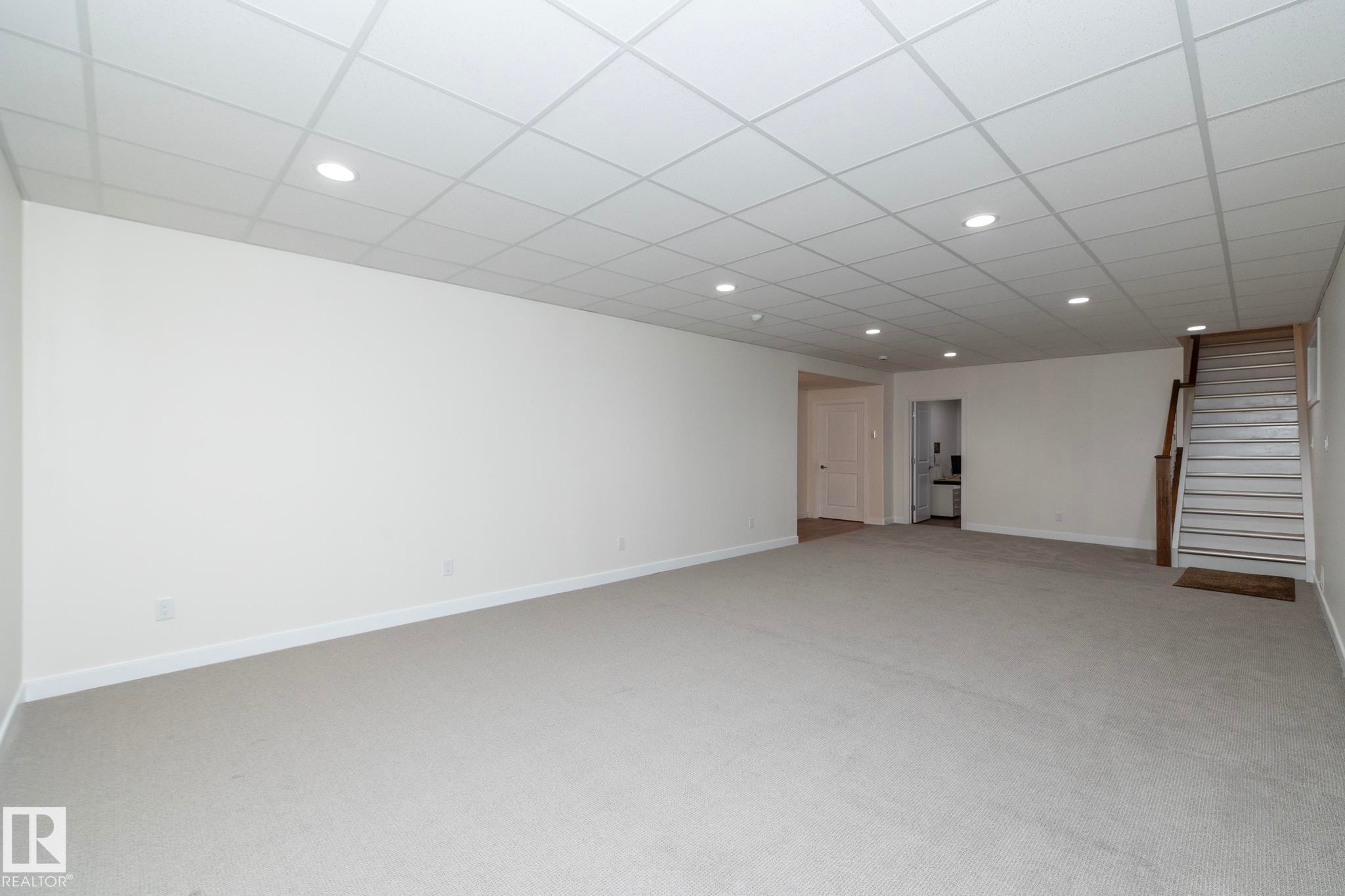 Expansive room featuring light-colored carpet flooring, white walls, and a drop ceiling with recessed lighting - 307 Ravine Close, Devon, AB - Indoor Photo Showing Other Room