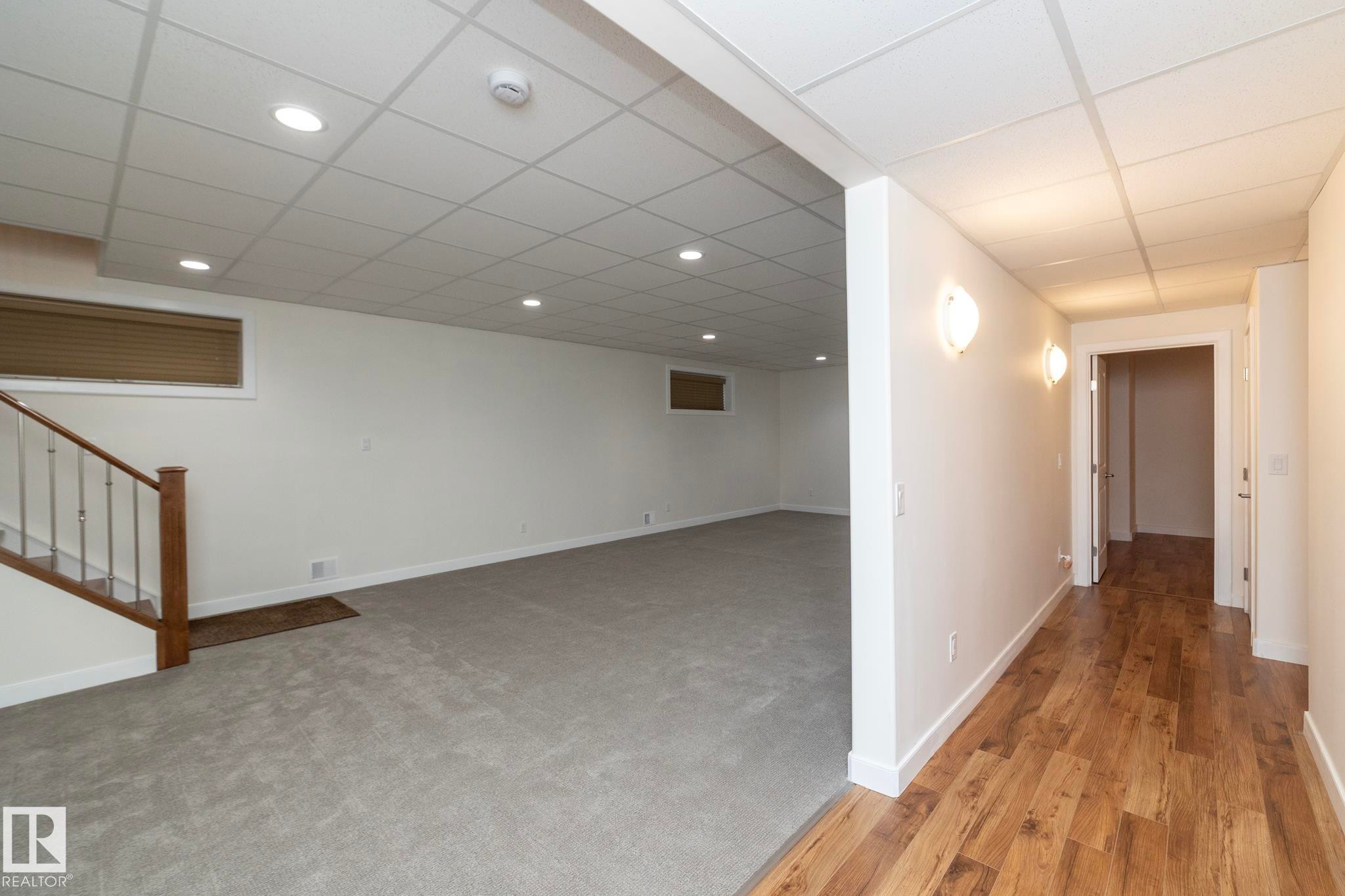 The property features a spacious room with light grey carpeting and recessed lighting - 307 Ravine Close, Devon, AB - Indoor Photo Showing Other Room