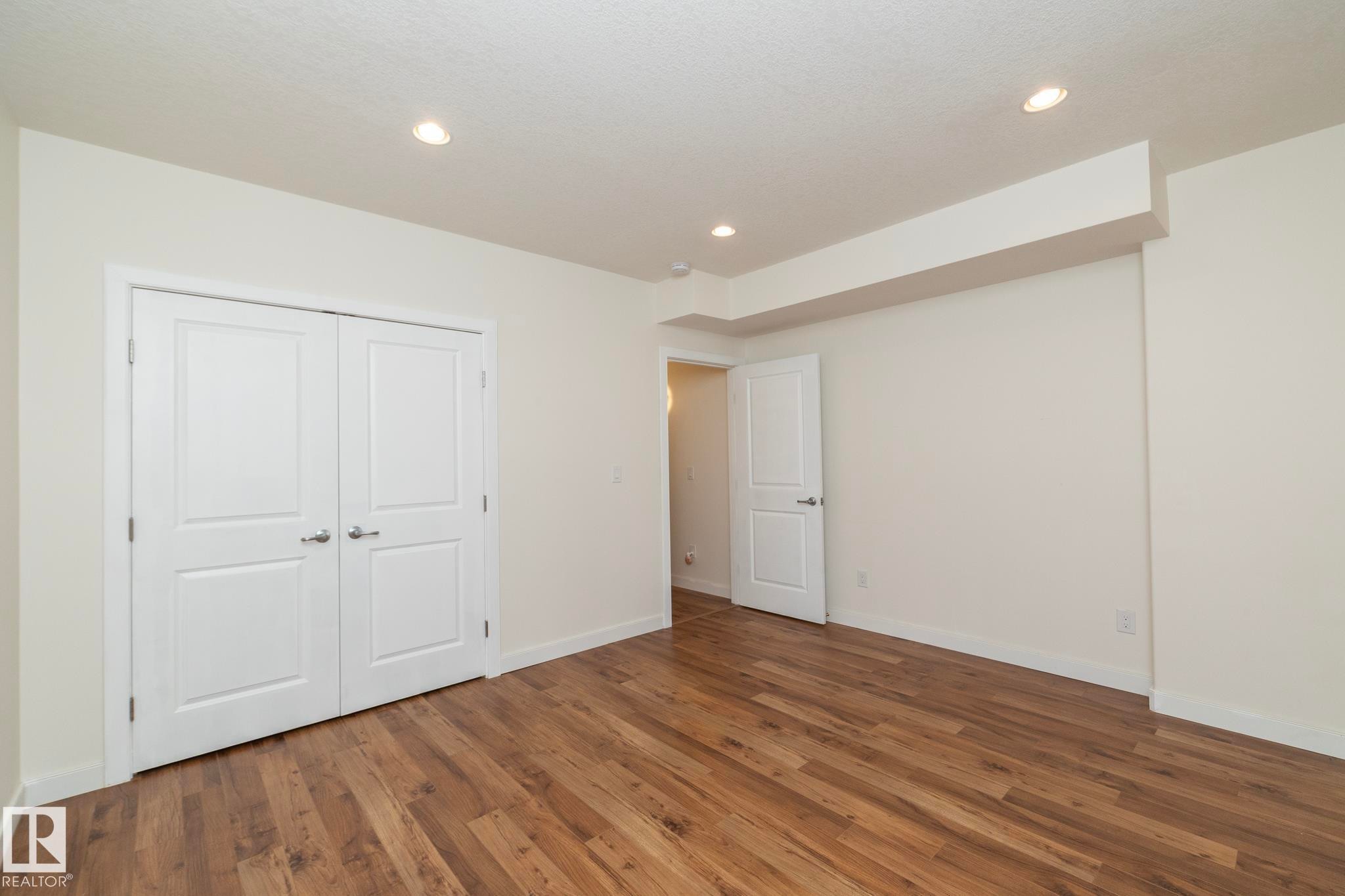 This room features wood-look flooring, white walls, and recessed lighting - 307 Ravine Close, Devon, AB - Indoor Photo Showing Other Room