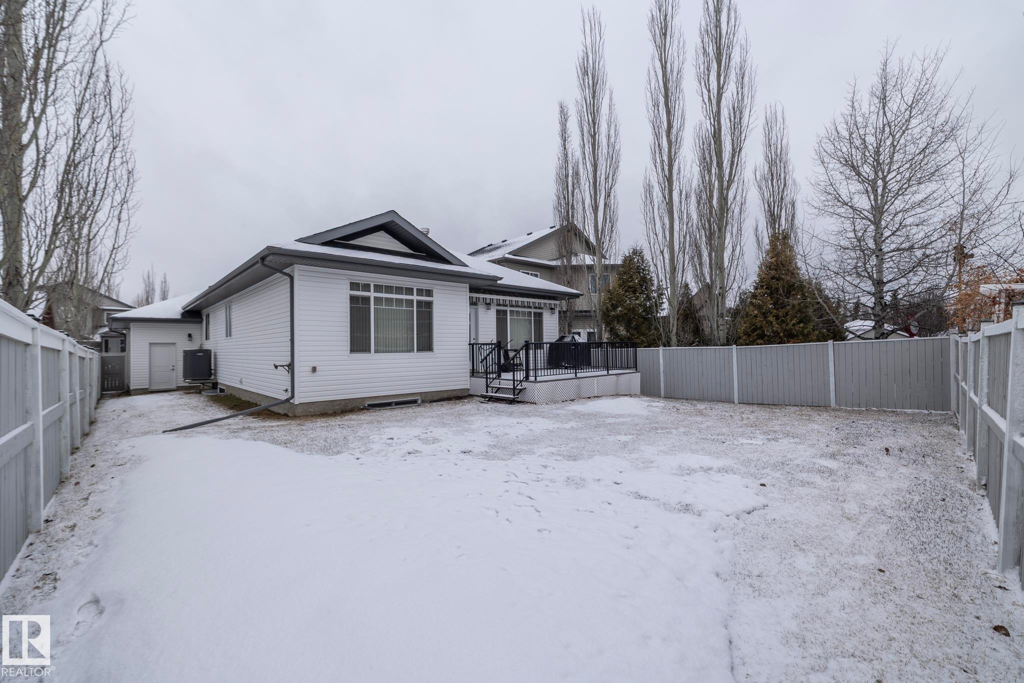 The property features a fenced backyard with a patio deck, offering privacy and outdoor living space - 307 Ravine Close, Devon, AB - Outdoor