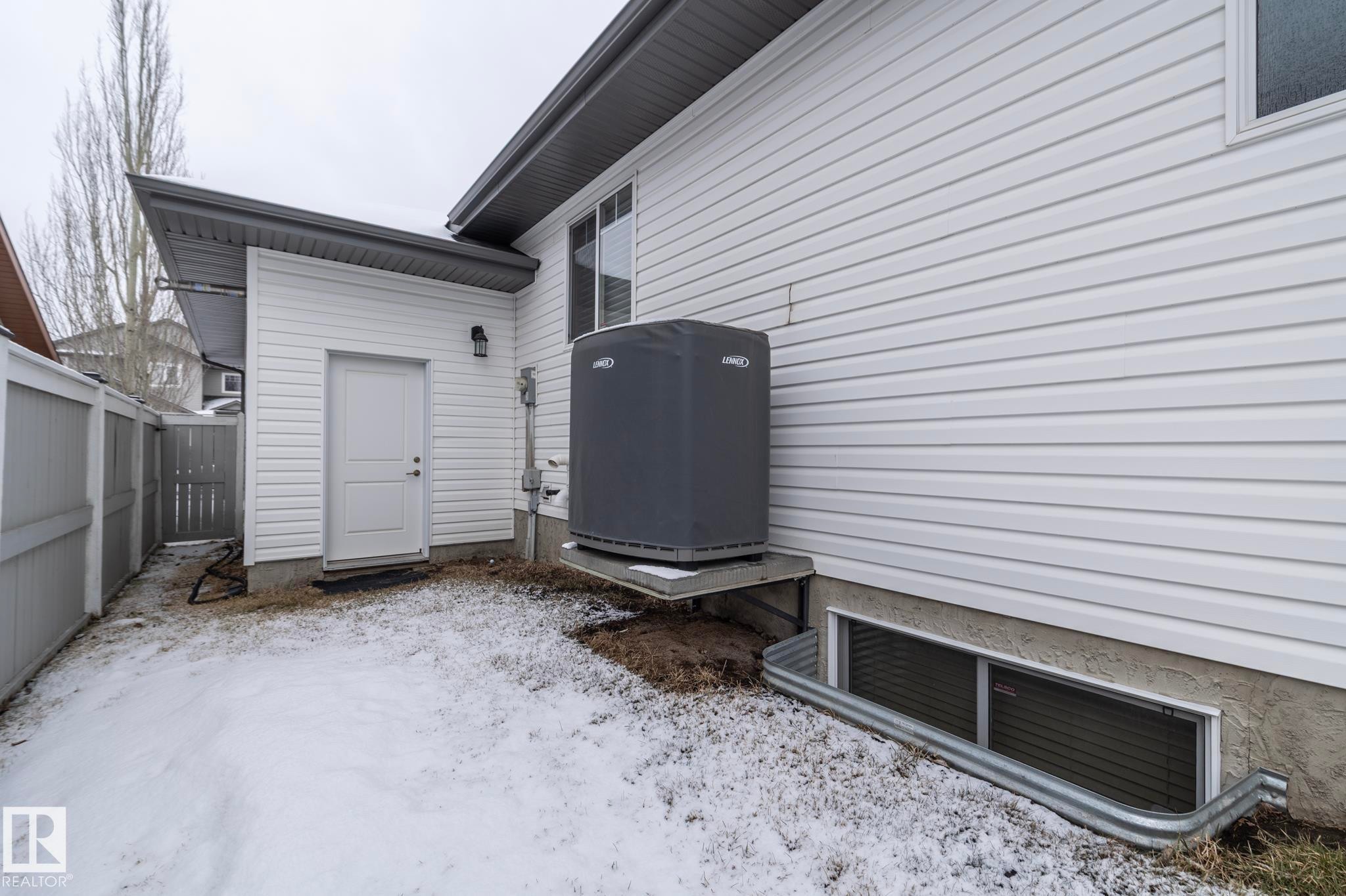 The property features white siding, a window, and a white exterior door - 307 Ravine Close, Devon, AB - Outdoor With Exterior