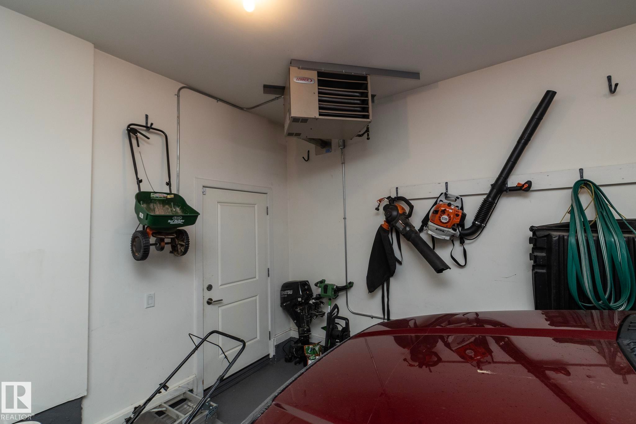 The garage features white walls, a white door, and a mounted heating unit - 307 Ravine Close, Devon, AB - Indoor