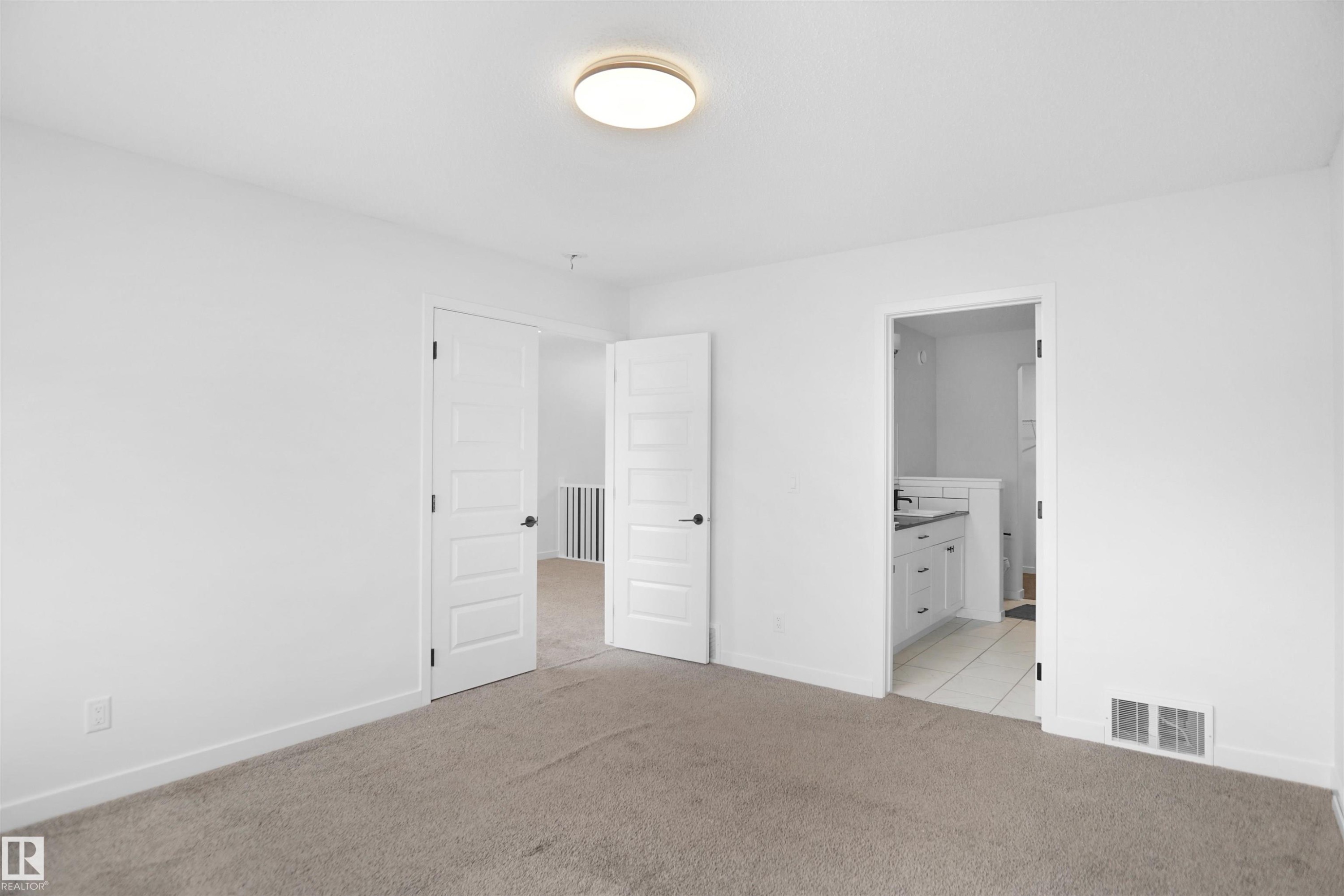 This room features light-colored carpeting, a ceiling light fixture, and white walls - Edmonton, AB - Indoor Photo Showing Other Room
