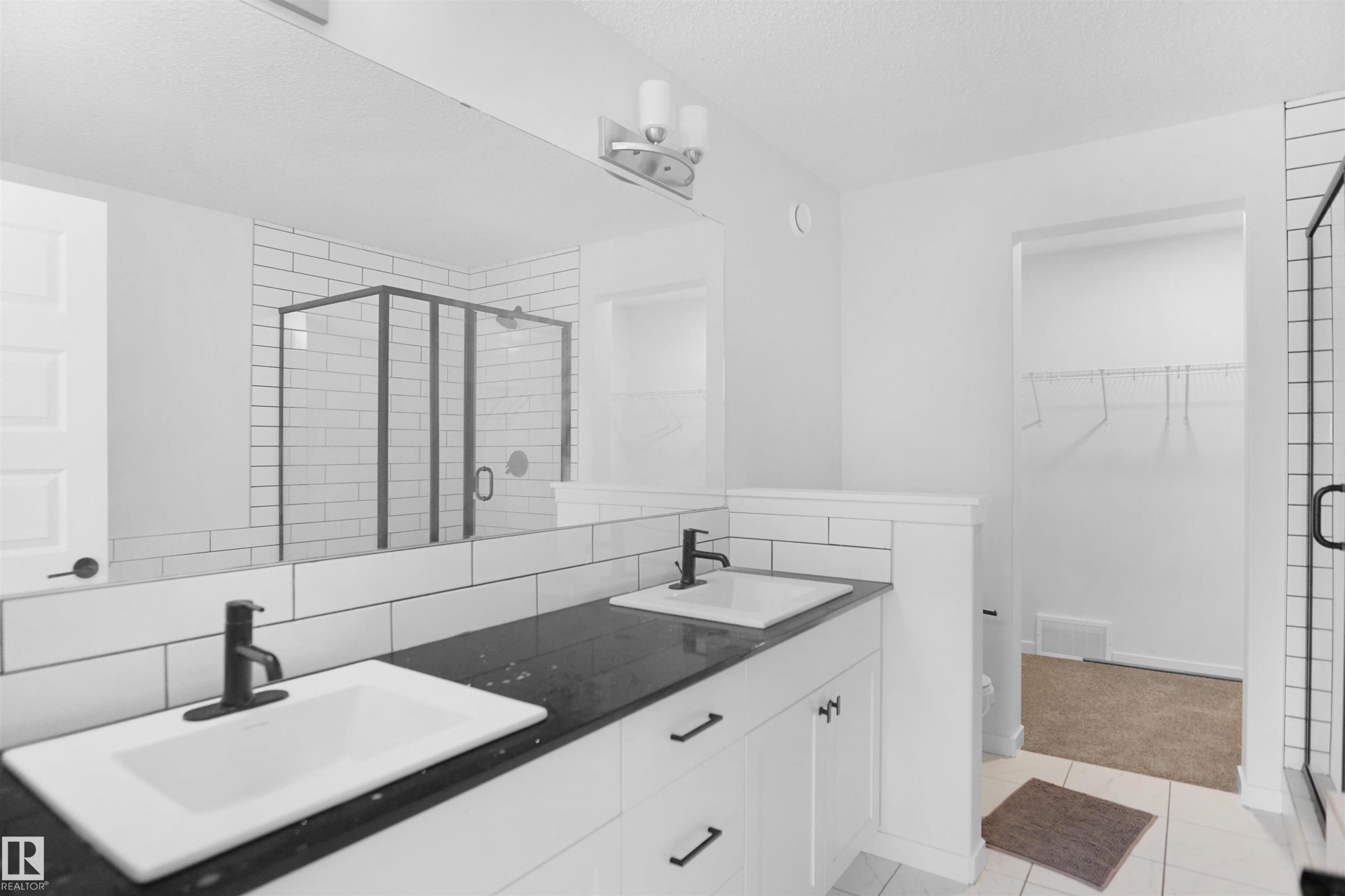 The bathroom features a double vanity with matte black faucets, a dark countertop, and white cabinetry - Edmonton, AB - Indoor Photo Showing Bathroom