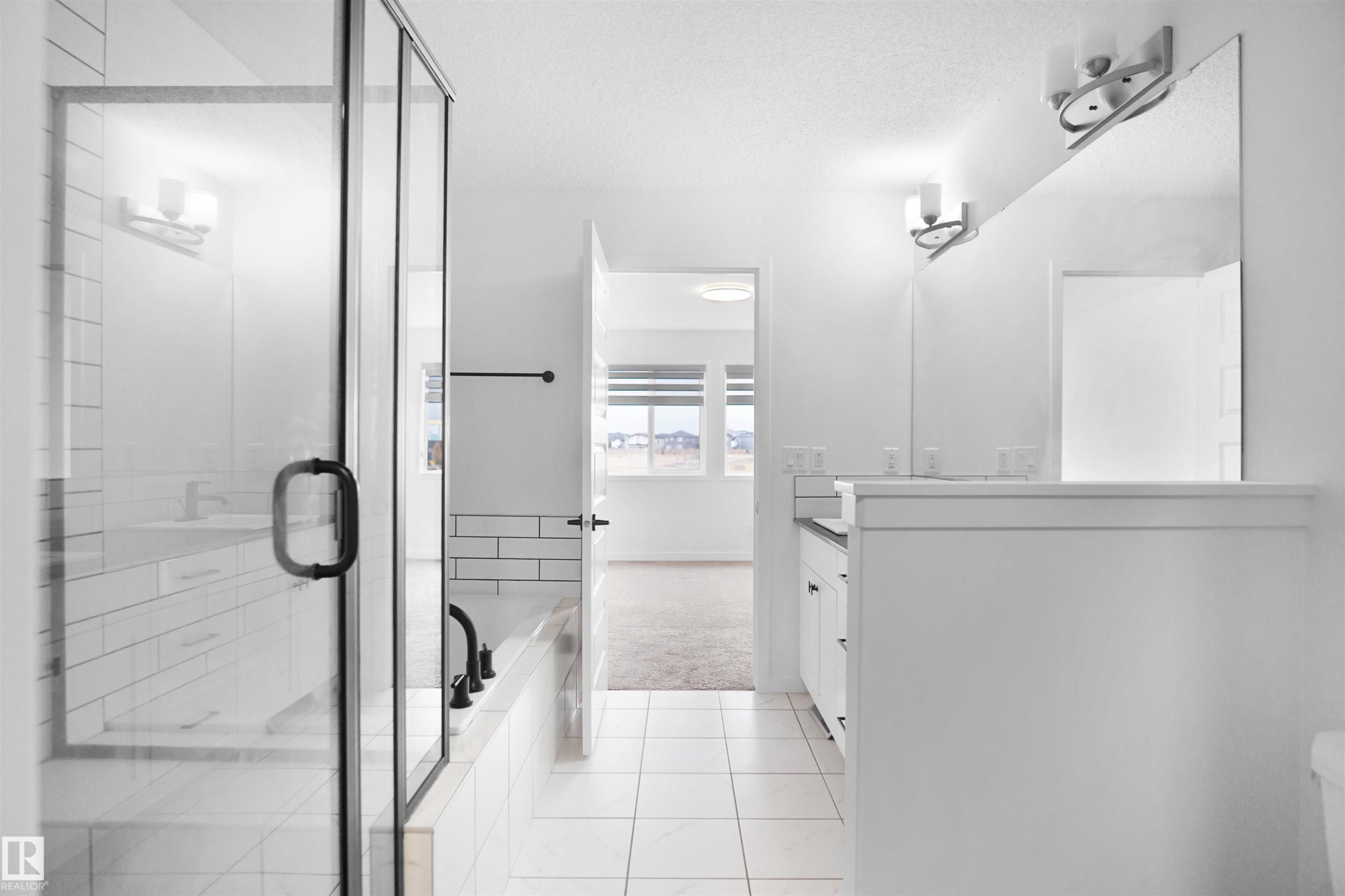 Bathroom featuring a glass-enclosed shower, a separate bathtub, and a double vanity with an expansive mirror - Edmonton, AB - Indoor Photo Showing Bathroom