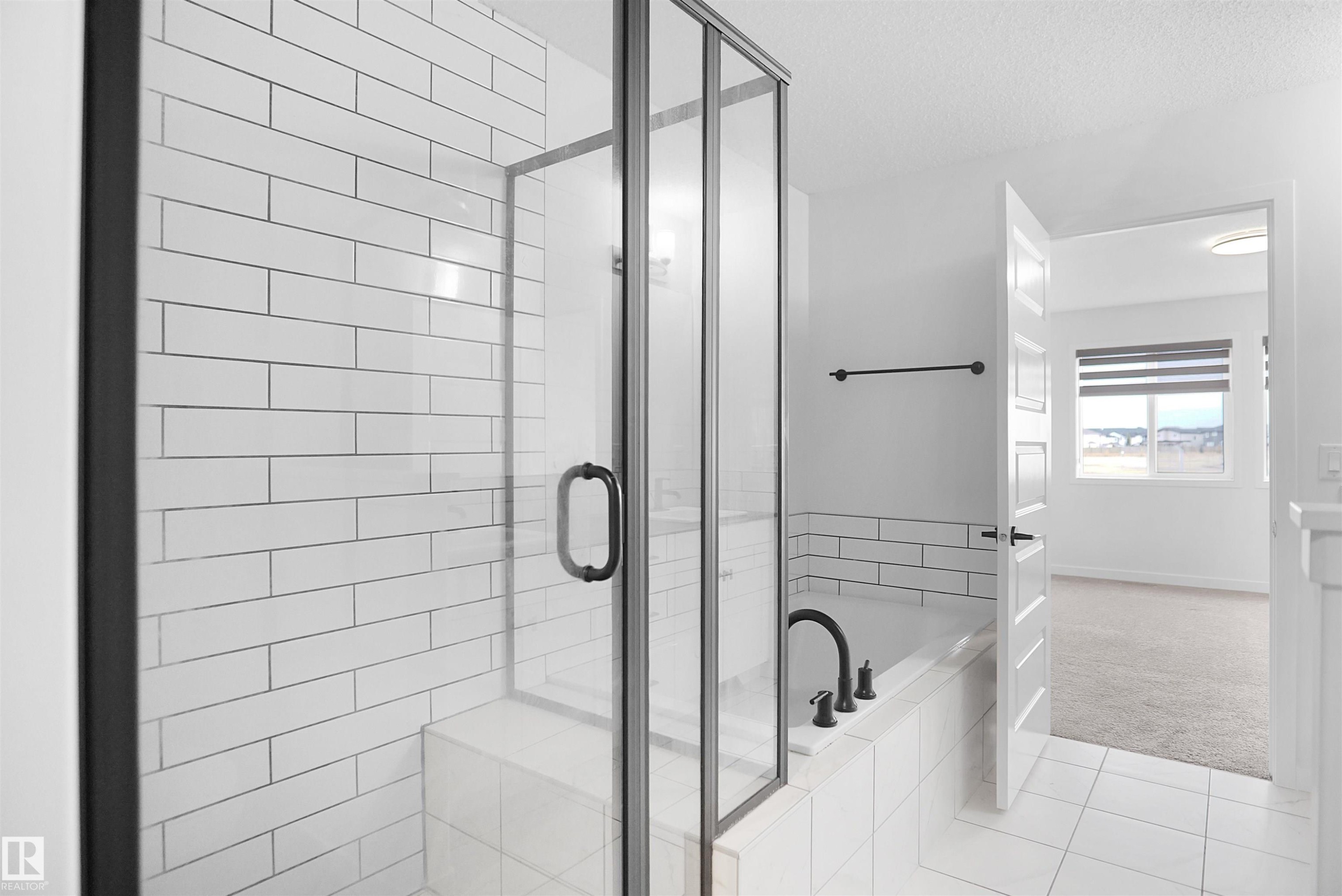 Bathroom featuring a glass-enclosed shower with subway tile, a bathtub with matte black fixtures, and white tile flooring - Edmonton, AB - Indoor Photo Showing Bathroom