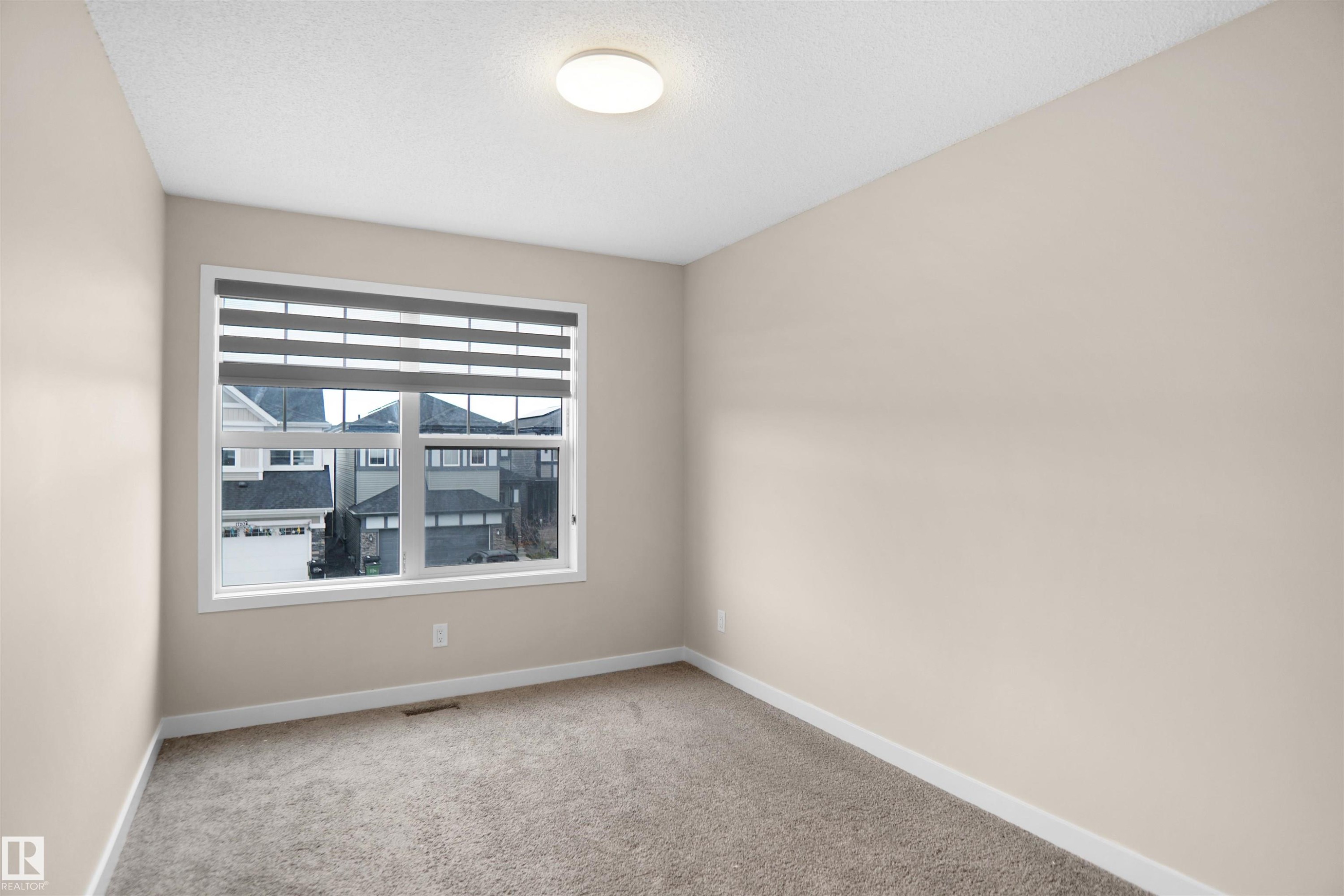 This room features a window with blinds, neutral-toned walls, and carpeted flooring - Edmonton, AB - Indoor Photo Showing Other Room