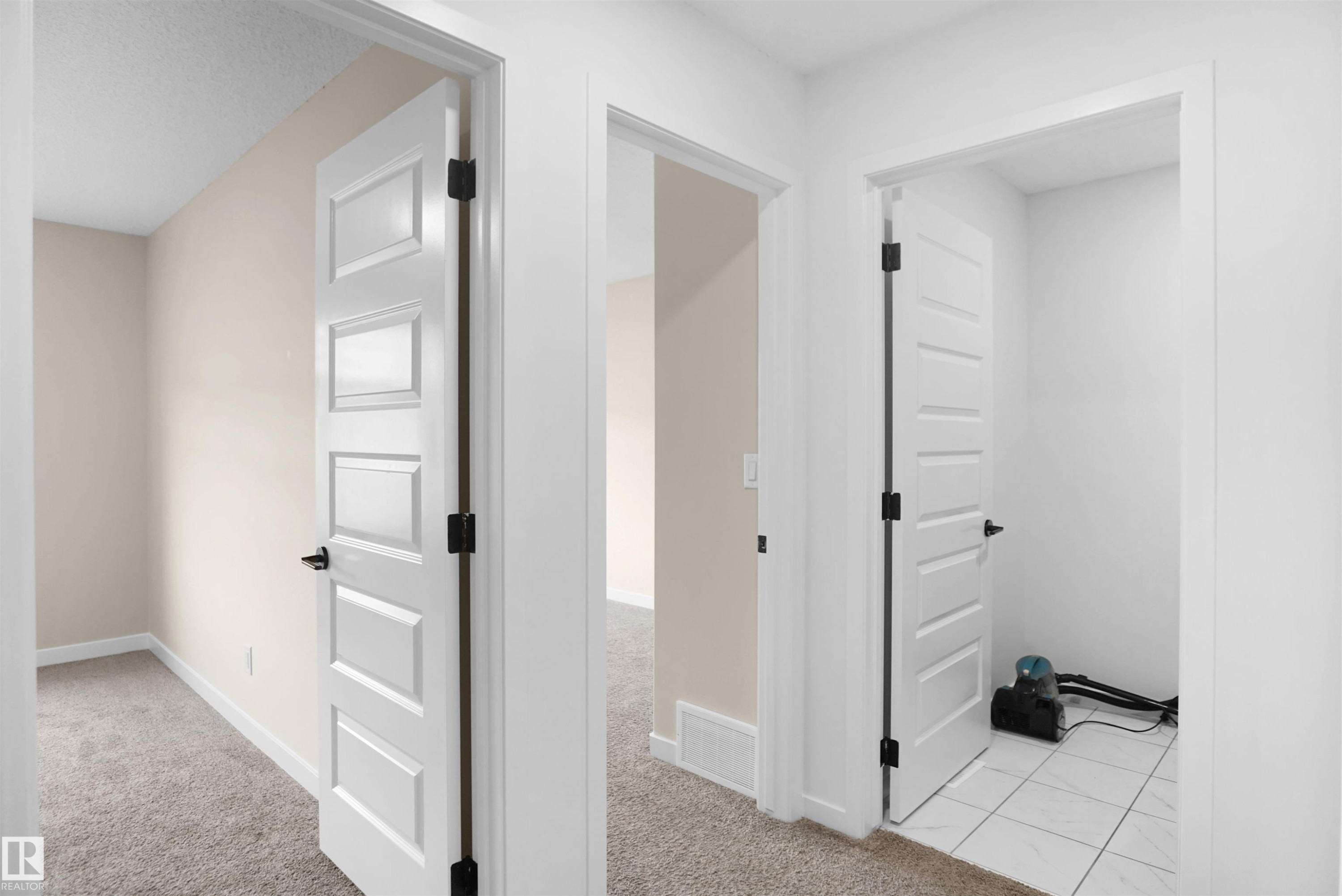 Hallway featuring light beige walls, white trim, and doors with matte black hardware - Edmonton, AB - Indoor Photo Showing Other Room