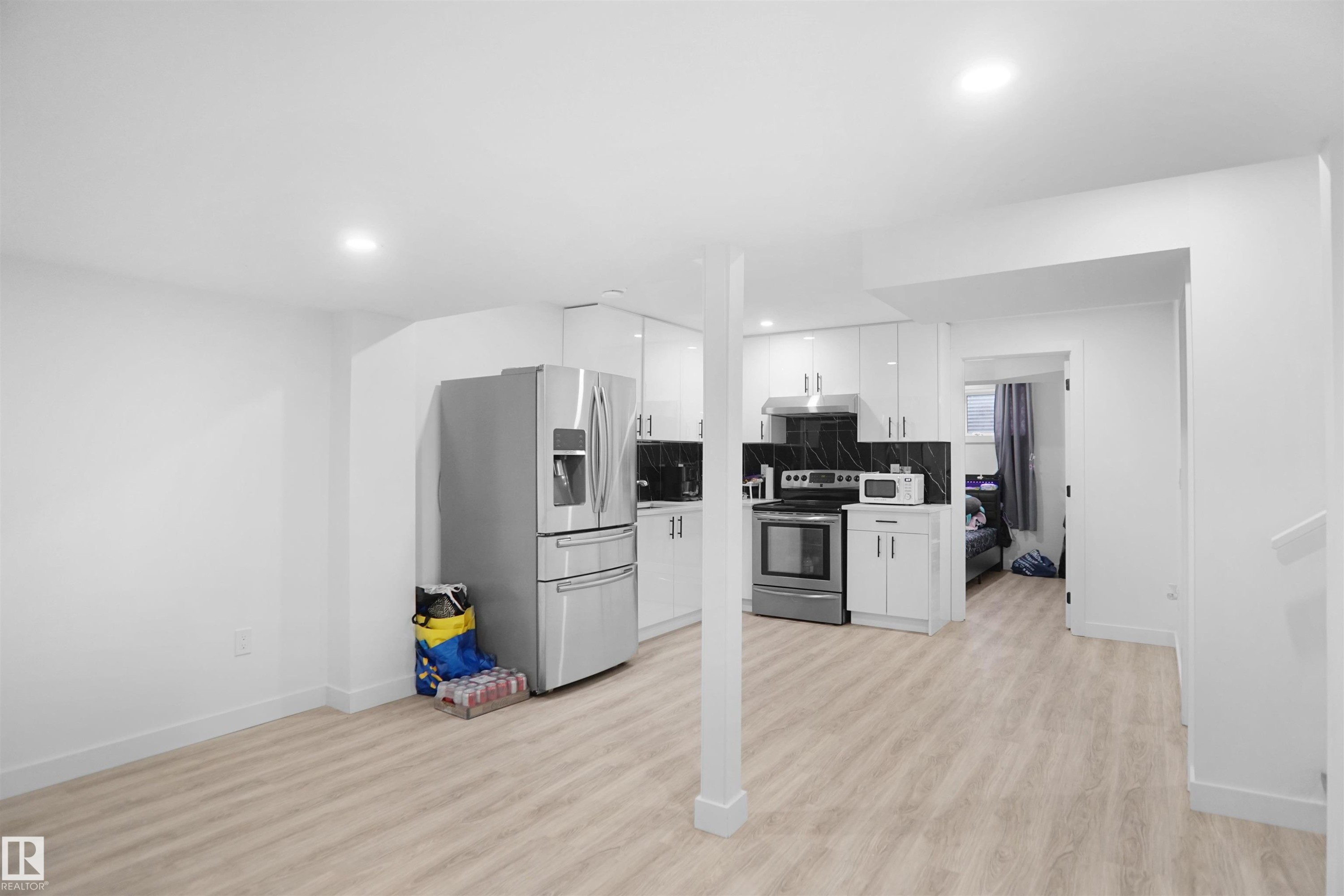 The property features a bright kitchen area with white cabinetry, stainless steel appliances, and a dark tile backsplash - Edmonton, AB - Indoor Photo Showing Kitchen