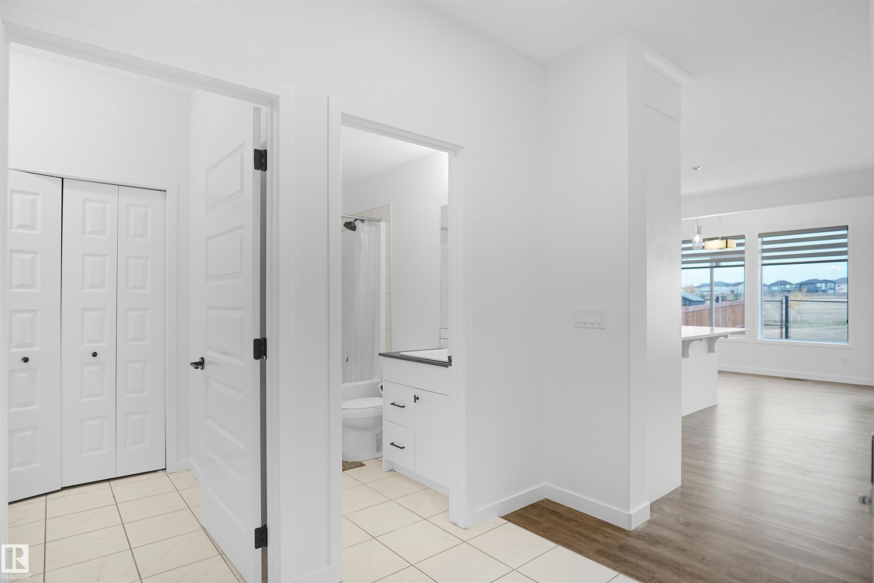 This interior features light-colored tile flooring, white walls, and white paneled doors with dark hardware - Edmonton, AB - Indoor Photo Showing Other Room