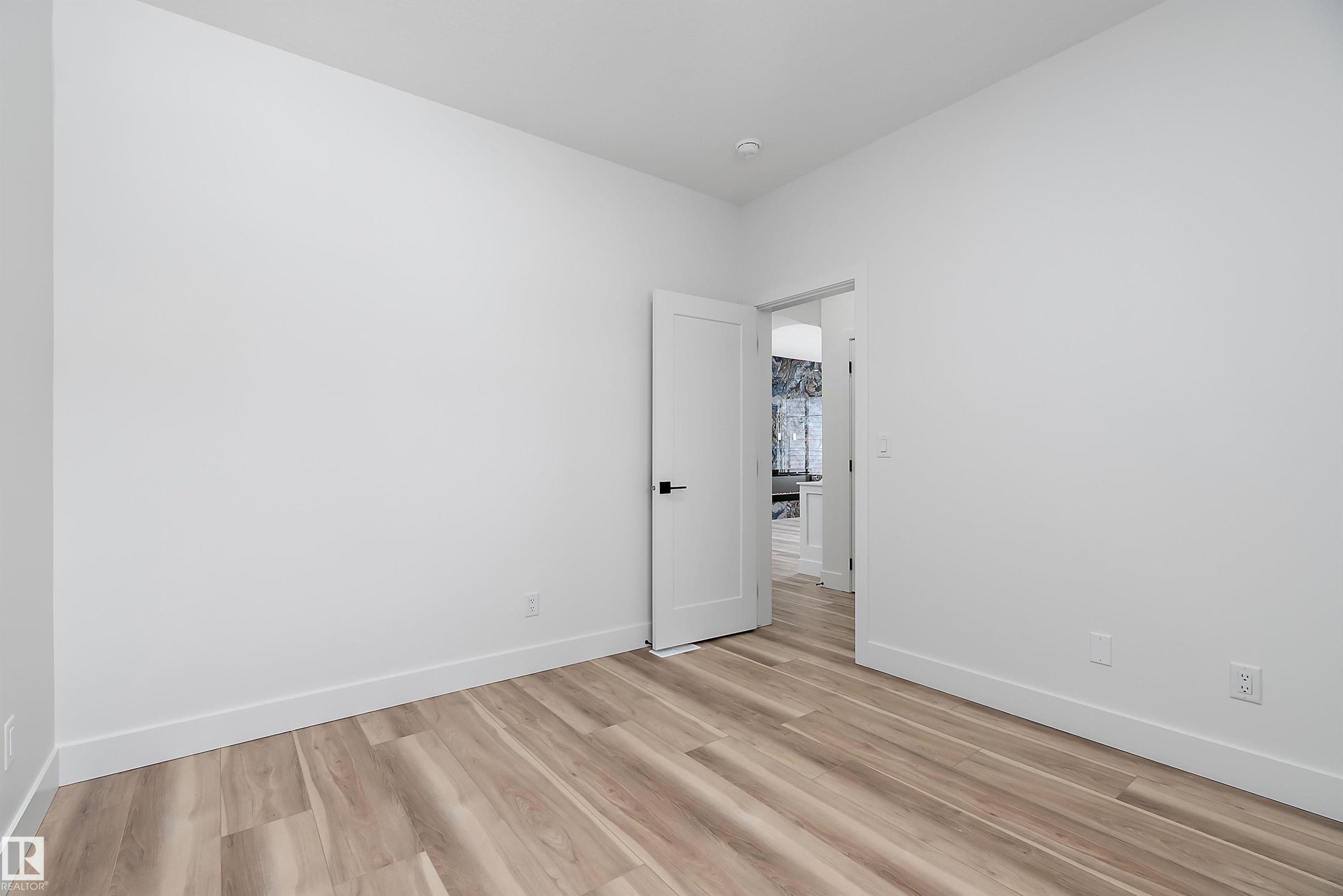 This room features light-colored plank flooring, white walls, and a white door with black hardware - 219 Crystal Creek Dr, Leduc, AB - Indoor Photo Showing Other Room