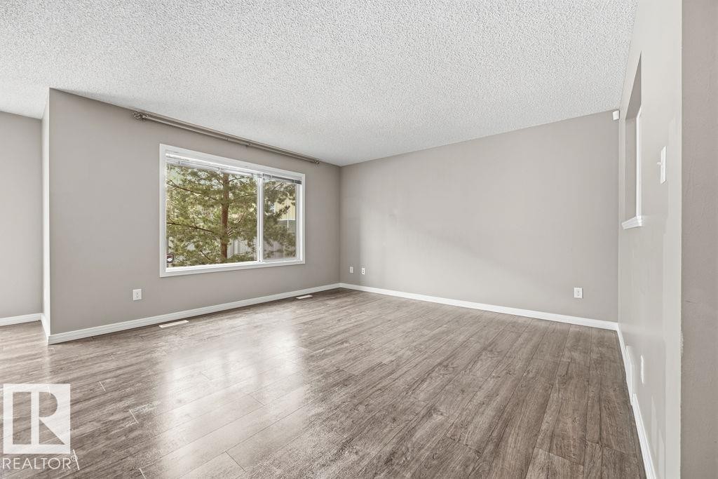 Interior hallway with carpeted flooring, light-colored walls, and a staircase featuring white handrails - 7873 170A Avenue, Edmonton, AB - Indoor Photo Showing Other Room