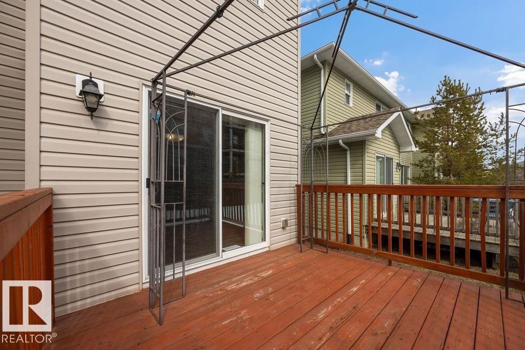 The property features a wooden deck with a finished railing, accessible through a glass sliding door - 7873 170A Avenue, Edmonton, AB - Outdoor With Deck Patio Veranda