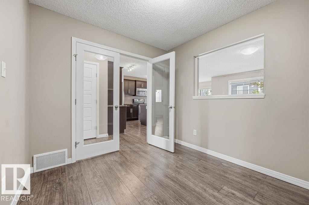 Spacious open-concept living area featuring a kitchen island with sink, stainless steel appliances, and wood-look flooring - 7873 170A Avenue, Edmonton, AB - Indoor Photo Showing Kitchen