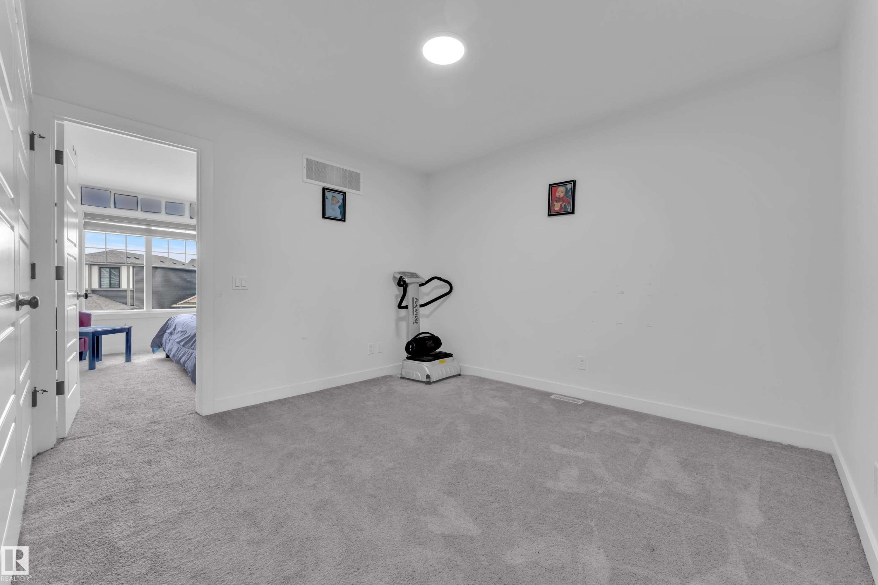 This versatile room features light gray carpeting, white walls, and a recessed ceiling light - 1645 Plum Circle, Edmonton, AB - Indoor