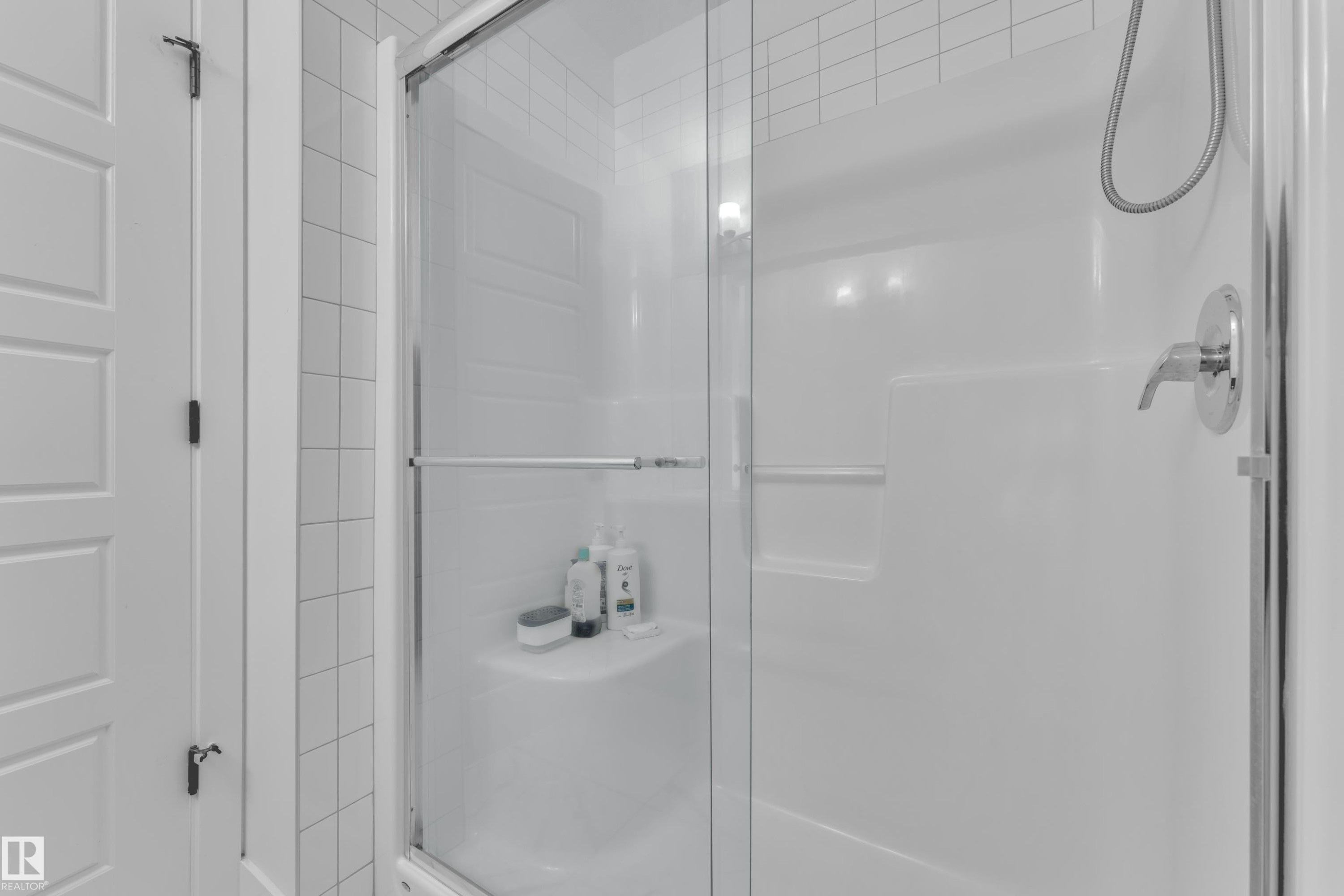 Shower featuring a glass enclosure, white tile surround, and built-in shelving - 1645 Plum Circle, Edmonton, AB - Indoor Photo Showing Bathroom