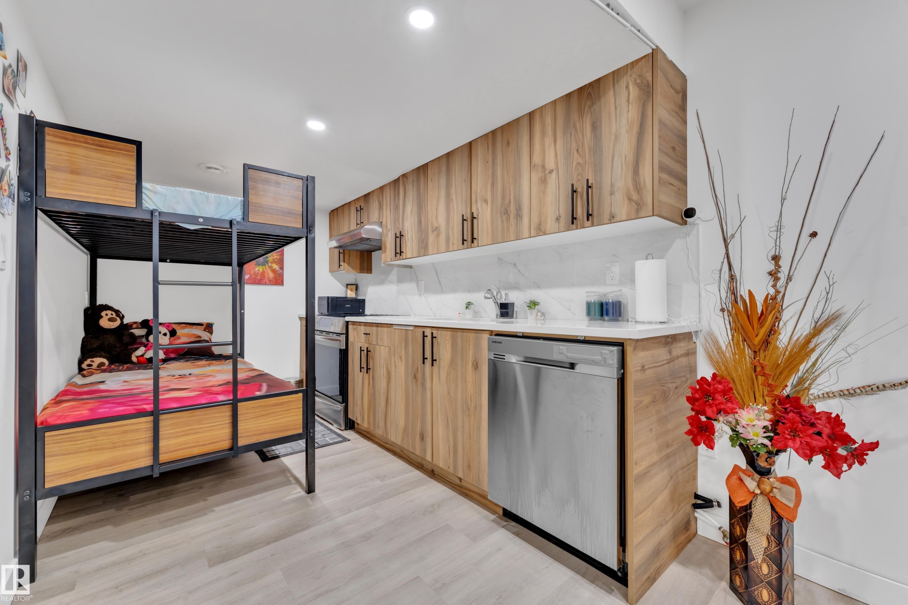 This functional space features wood-look cabinetry, a stainless steel dishwasher, and light-colored flooring - 1645 Plum Circle, Edmonton, AB - Indoor Photo Showing Kitchen